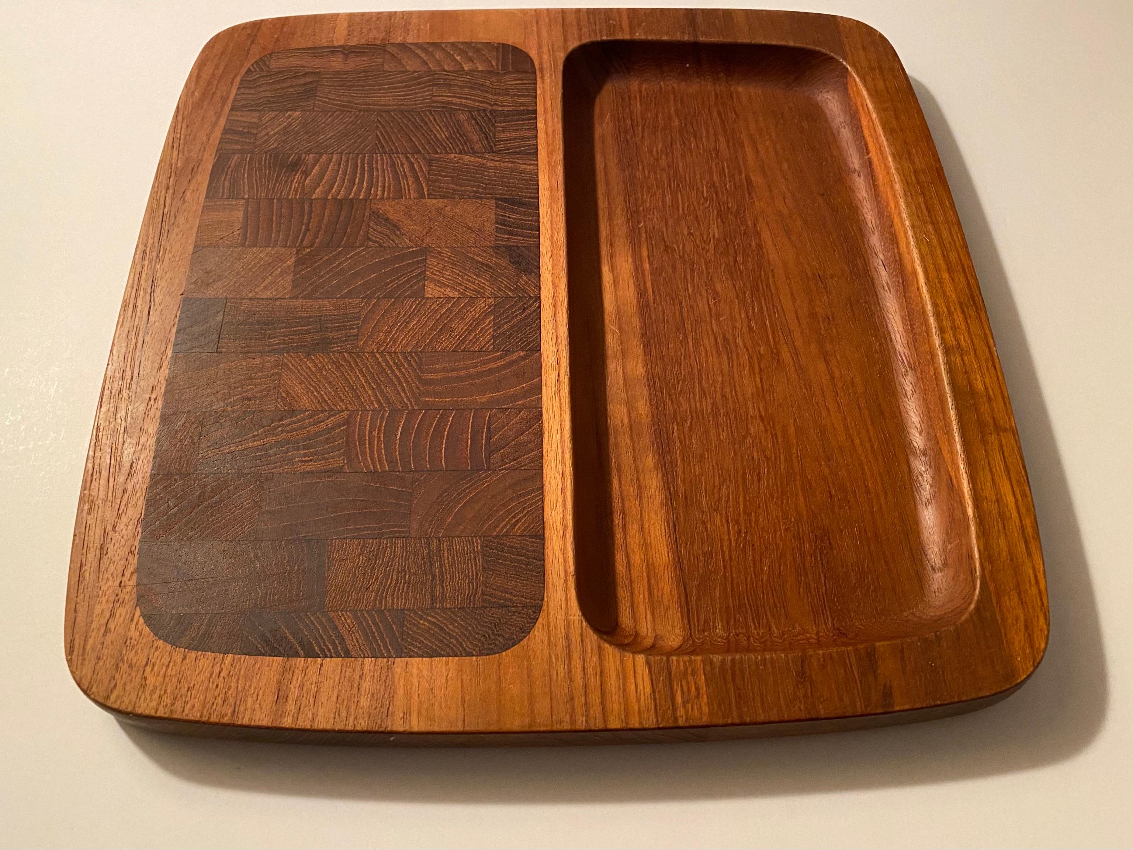A divided teak wood tray with an end-grain teak cutting surface and a recessed section, designed by Jens H. Quistgaard for Dansk. Branded 