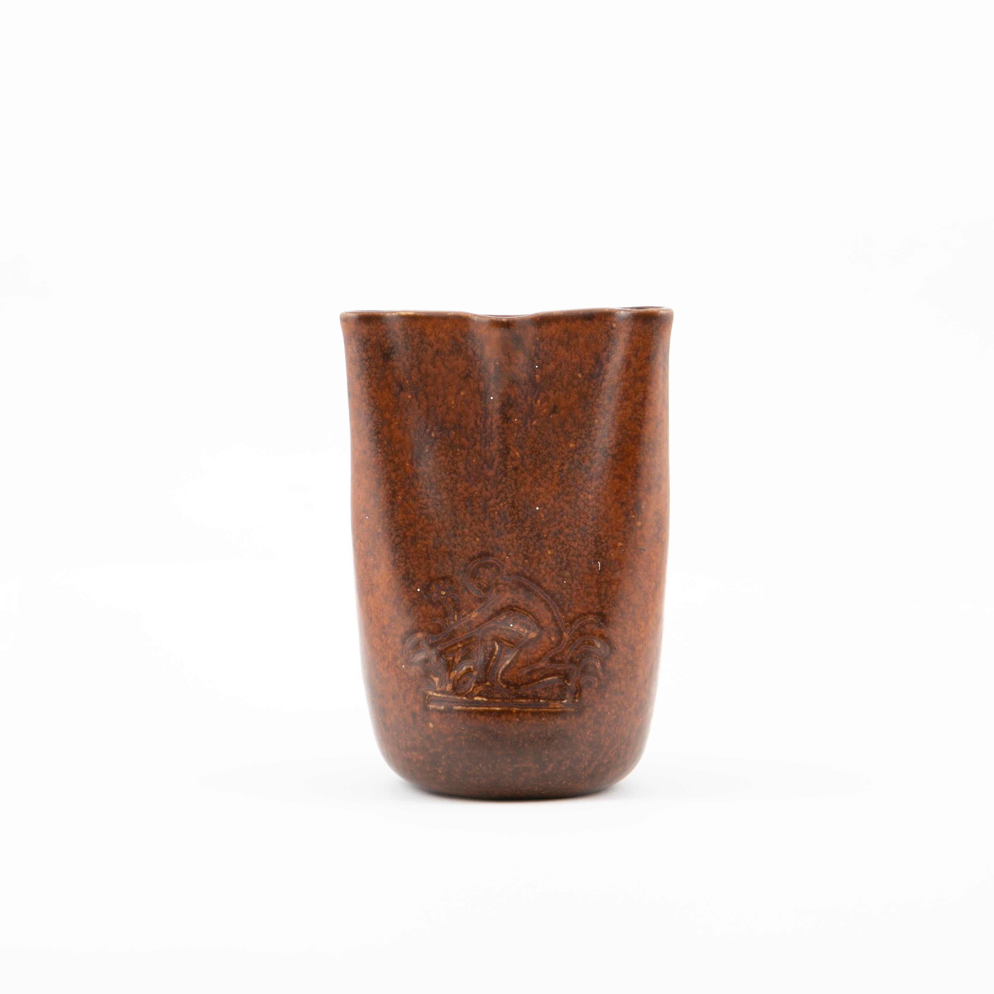 Jens Jakob Bregnø, Danish 1877-1946

A stoneware carnation vase with maroon glaze. At the top three holes for carnations / single flower. Presumably on of a kind.
On one side side relief of a person kneeling in a flower bed.

Signed with monogram