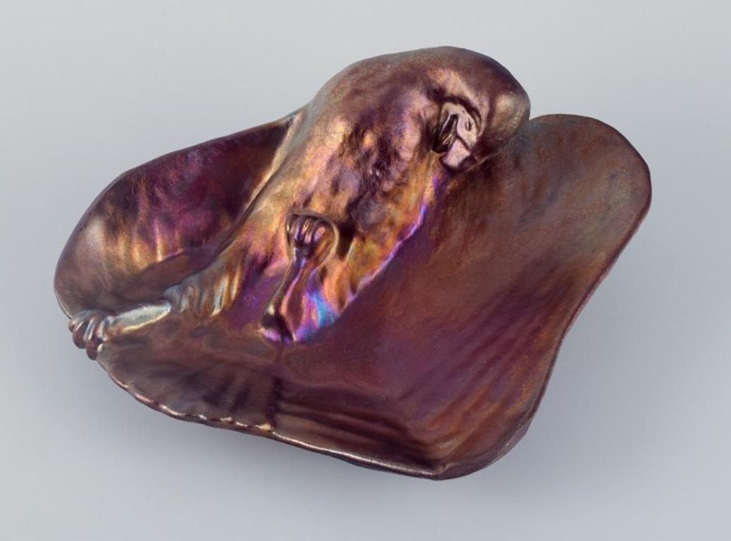 Jens Petersen, unique Art Nouveau ceramic bowl with wall bracket.
Modelled with a parrot. 
Metallic luster glaze.
Signed JP.
Ca. 1920.
Dimensions: W 32.5 cm x H 25.5 cm x depth 11.5 cm.