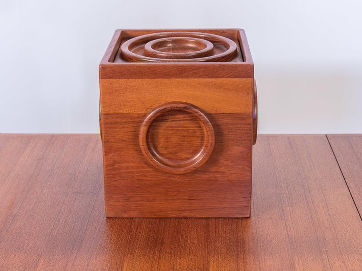 Awesome Jens Quistgaard cube ice bucket with original tongs for Dansk. Solid teak construction with carved circle details on all sides. Top features a raised bullseye design for the lid, with a fitted waterproof black plastic interior. Ice bucket