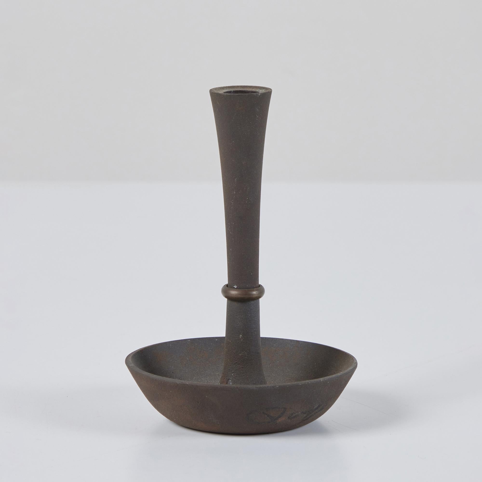 Single iron and brass candle holder by Jens Quistgaard for Dansk. This example was produced in Denmark in the 1960s for only a short time. It features a cast iron body and round curved base, with a patinated brass ring around the stem.
Impressed 