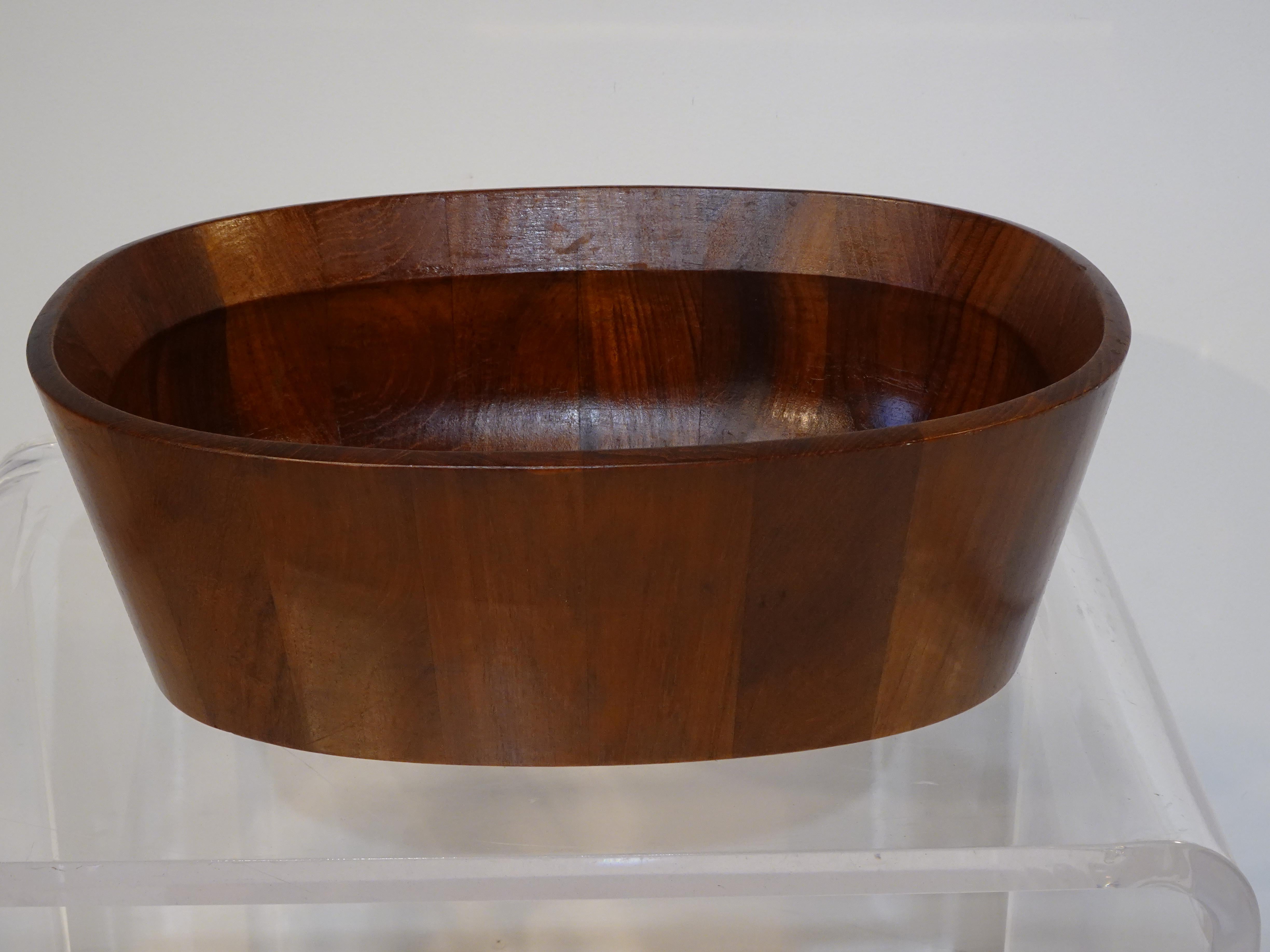 A darker toned teak wood oval shaped bowl designed by Jens H. Quistgaard who is known for his earthy sculptural pepper mills, bowls, serving pieces and furniture. This earlier piece having the 4 duck markings and Dansk Designs Denmark JHQ branded to