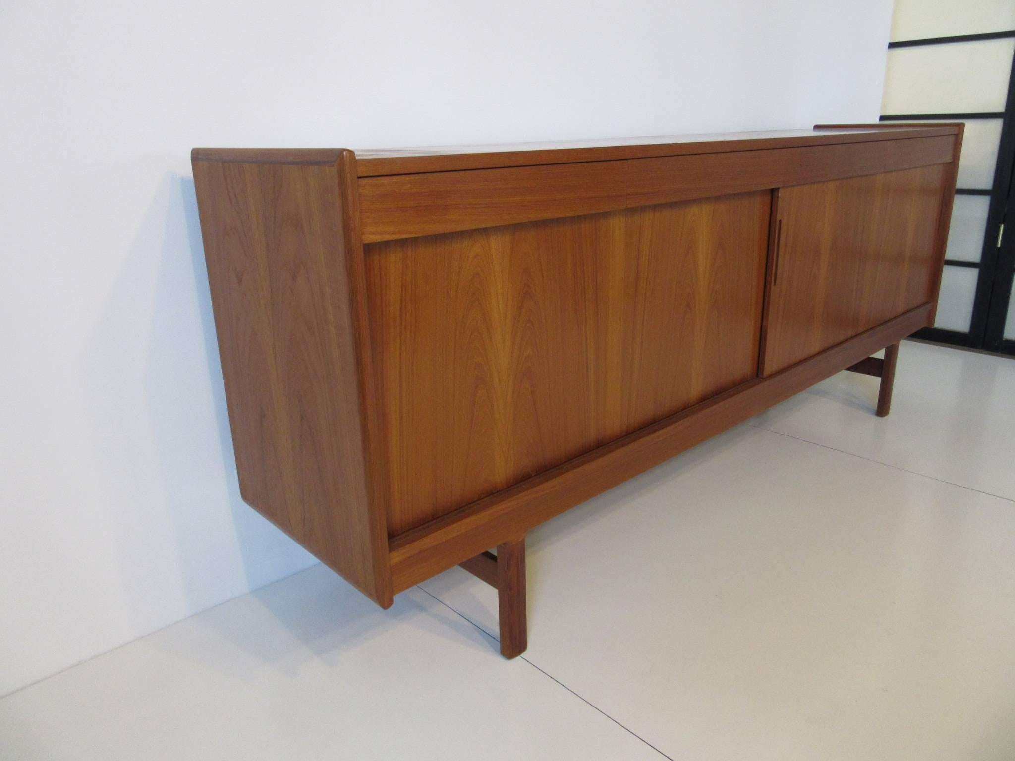 A well crafted teakwood sever or credenza with four upper drawers for storage and two lower sliding door with storage and adjustable shelves. On one side are four smaller pull out drawers all done in a lighter wood , the back of the piece is also