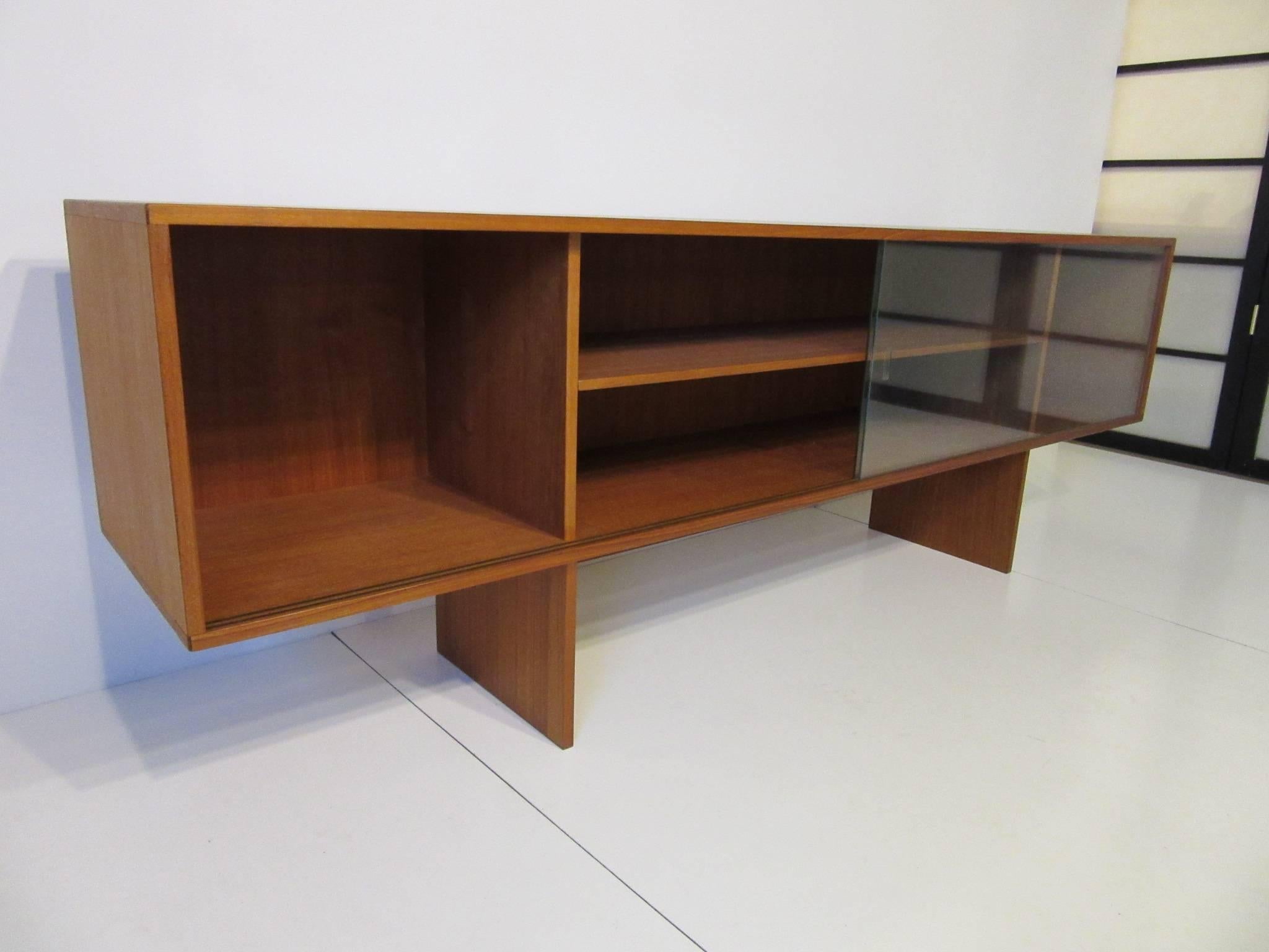 A teak wood bookcase with sliding glass doors by Jens Quistgaard for Lovig, a sleek and low profile design which retains the manufactures label Danish Design Lovig made in Denmark.