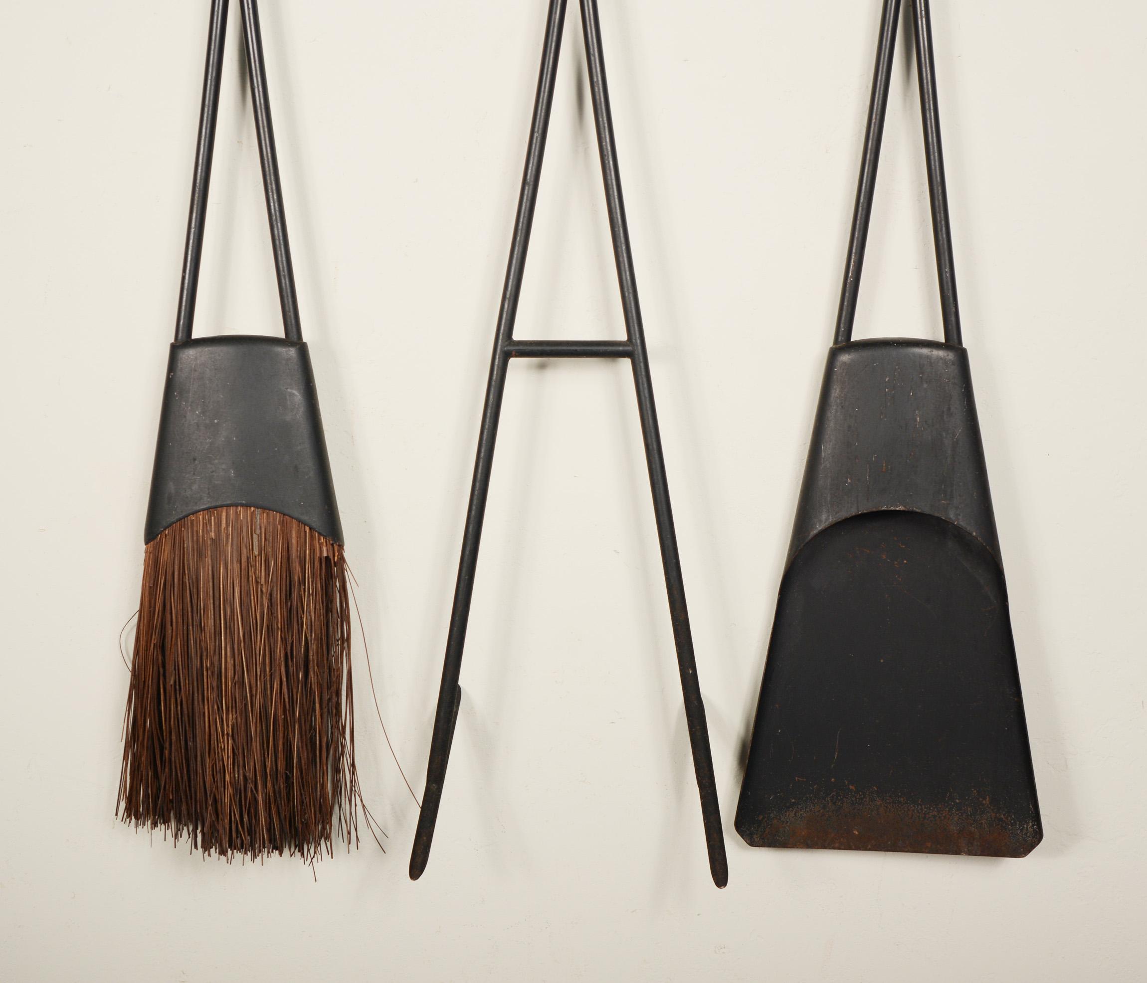 Rare set of Dansk fireplace tools designed by Jens Quistgaard. These consist of a poker, broom and shovel and are held on a wall mounted rack. This set is in original condition. There is wear, paint loss, a little rust on the end of the shovel and