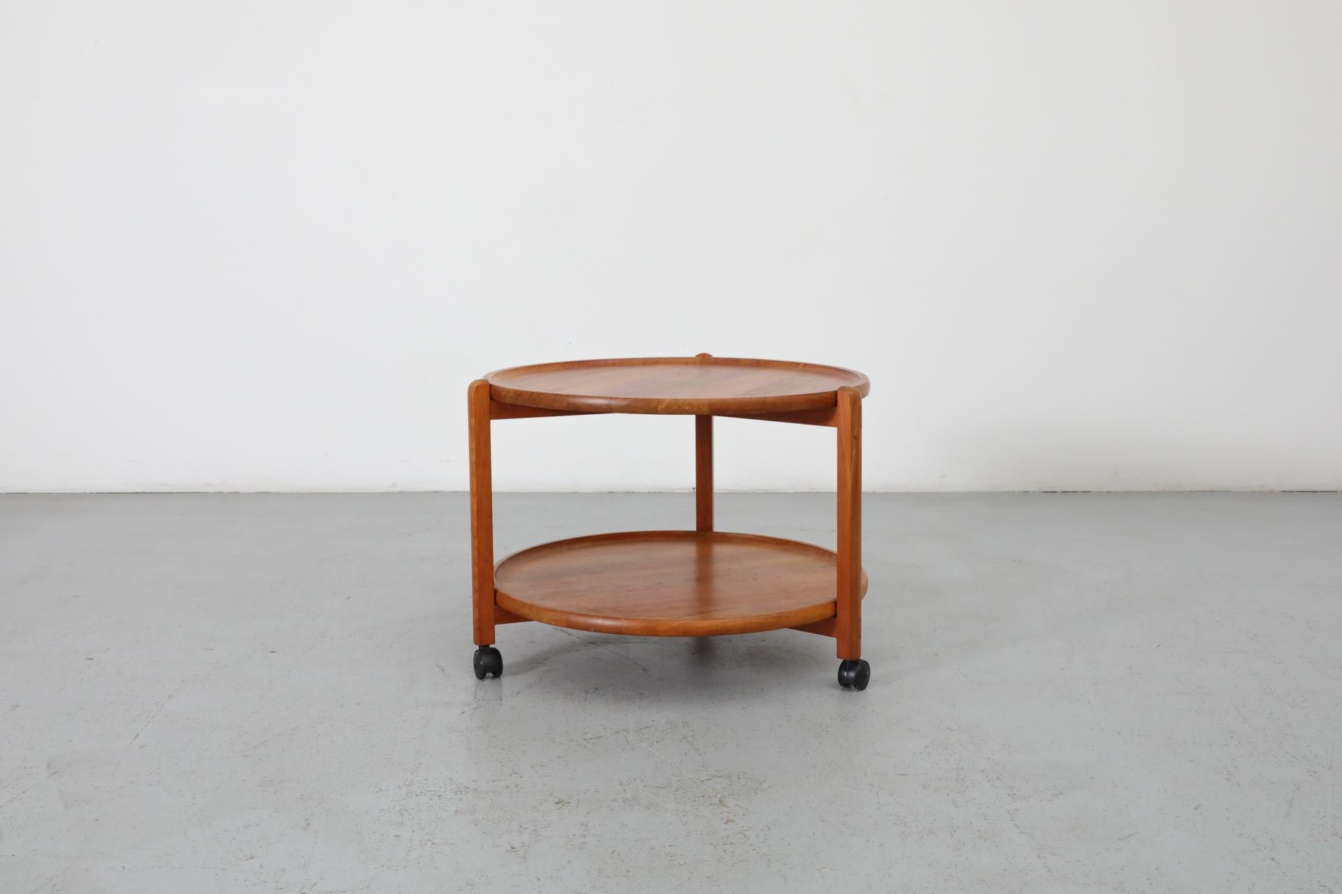 A lovely two-tiered Danish rolling bar cart with teak trays. The top tray is removable for quick service. Handsome carved edge detail with clean lines. In original condition, with wear consistent with it's age and use. Other bar carts are available