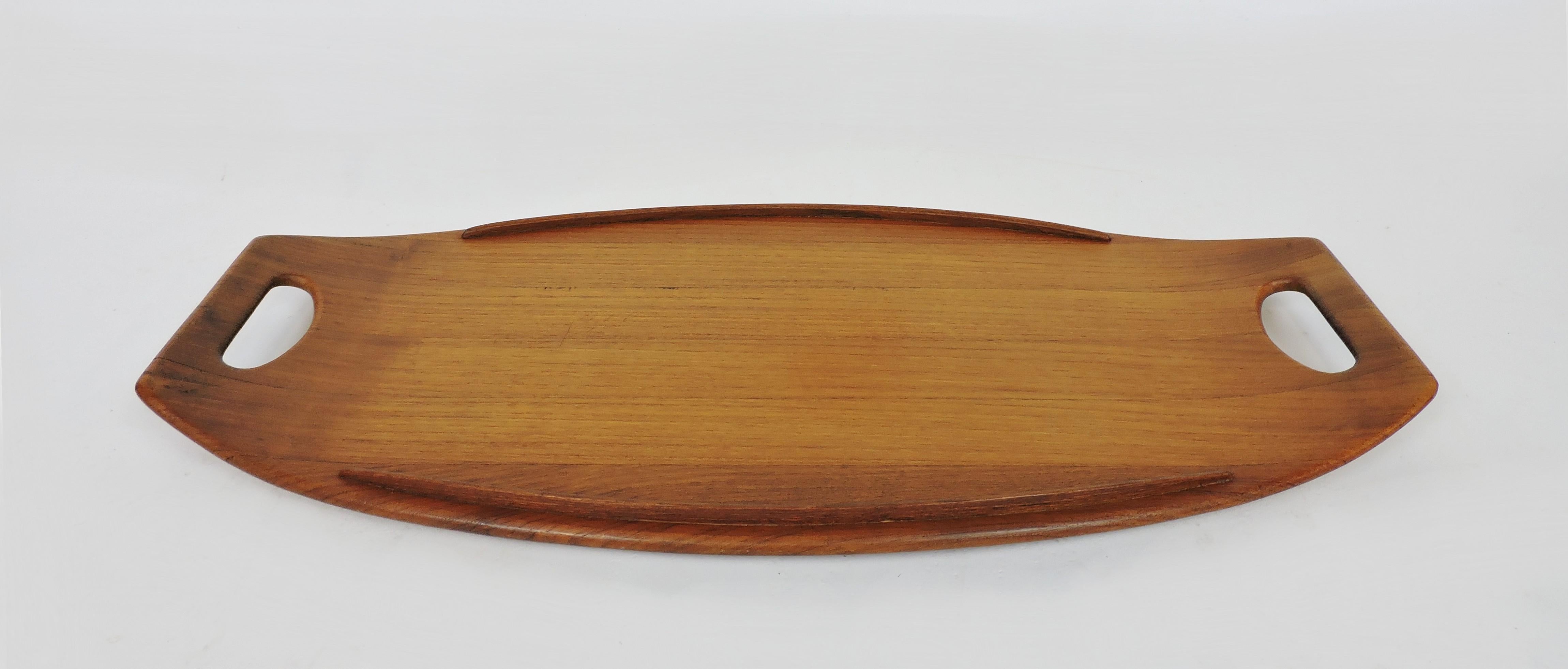 Beautiful and elegant staved teak serving tray designed by Jens Quistgaard and made in Denmark by Dansk. This large tray is 23.5 inches long with a graceful shape and an early Dansk mark. Serve in style!