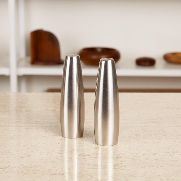 Pair of salt and pepper shakers by Jens Harald Quistgaard for Dansk, Denmark, circa 1960s. The Minimalist shakers feature a tapered cylindrical form in brushed stainless steel. To differentiate salt from pepper during use, one shaker has three