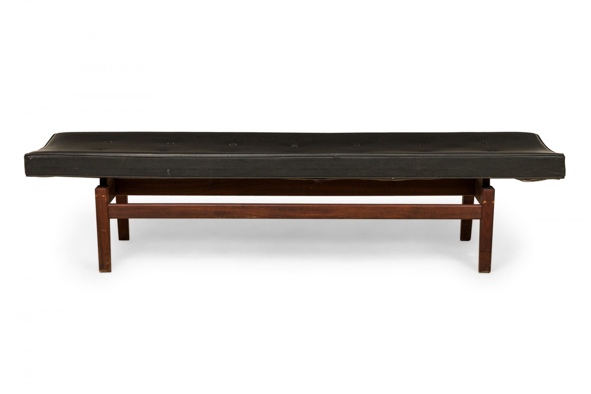 Danish Mid-Century floating bench with a black vinyl button tufted seat resting on a wooden floating frame base. (JENS RISOM).
 