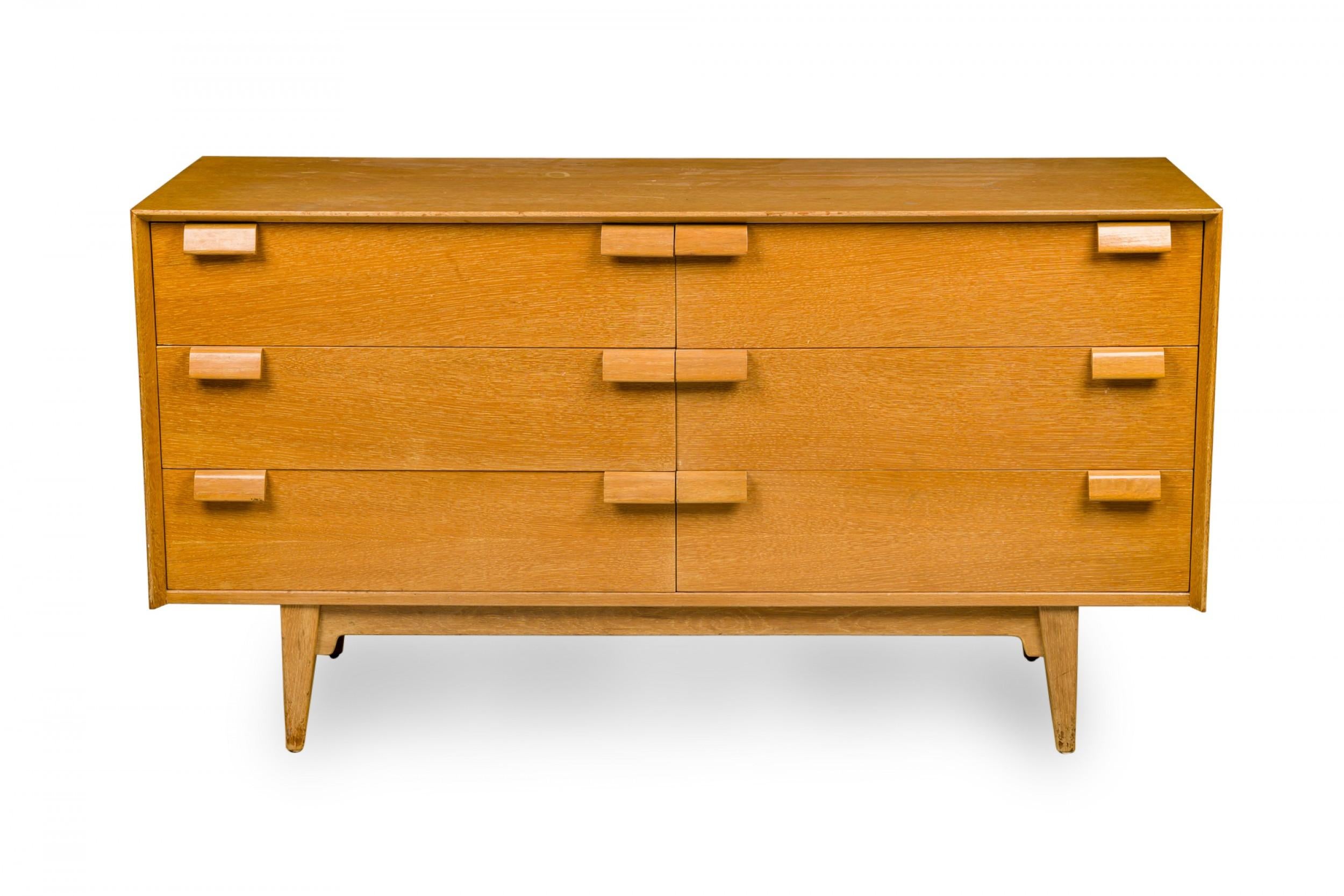 Danish Mid-Century dresser with 6 drawers with angled rectangular oak drawer pulls in a blond oak case resting on four tapered legs. (JENS RISOM).
 