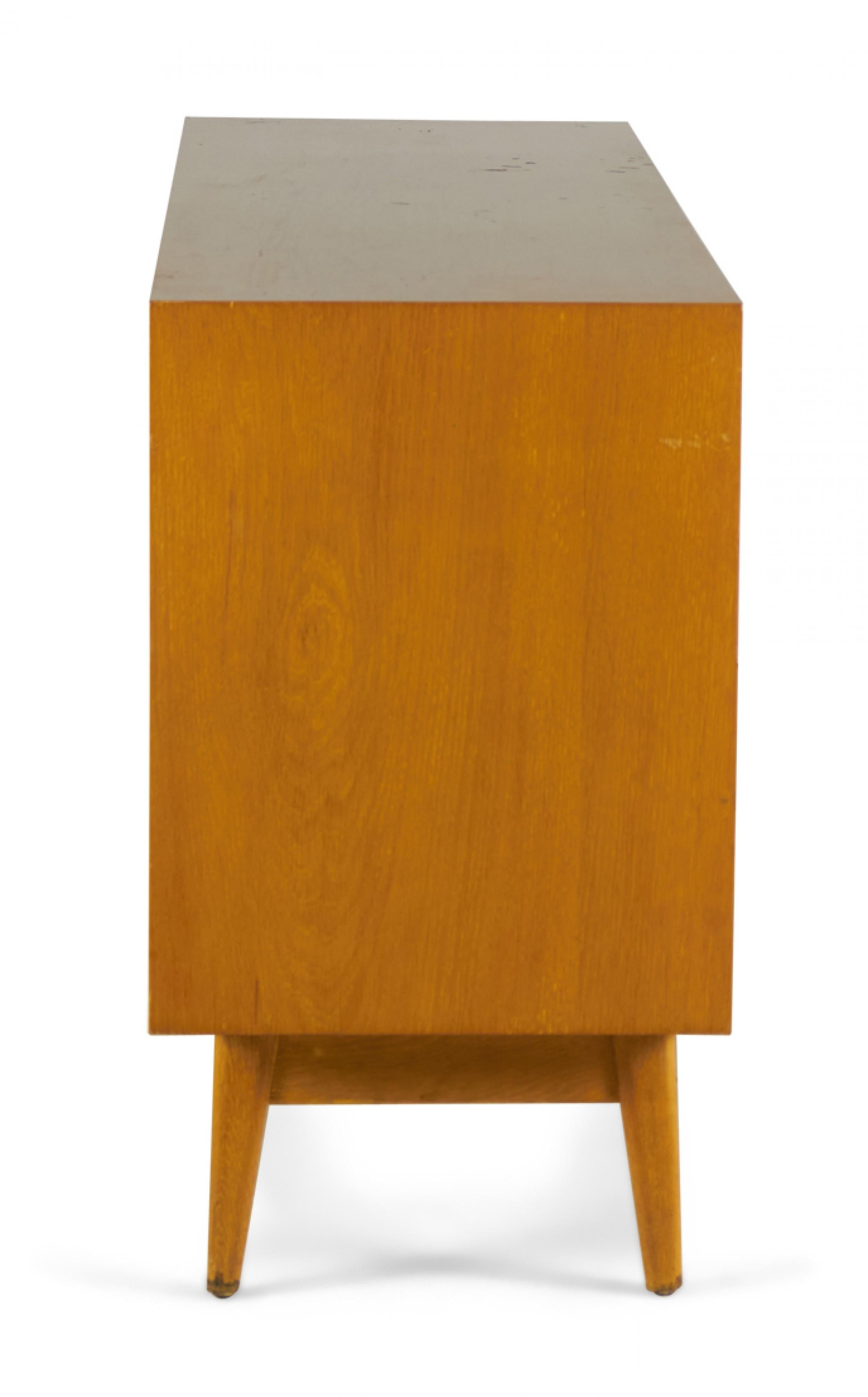 Danish Mid-Century dresser with 6 drawers with angled rectangular oak drawer pulls in a blond oak case resting on four tapered legs. (JENS RISOM)
