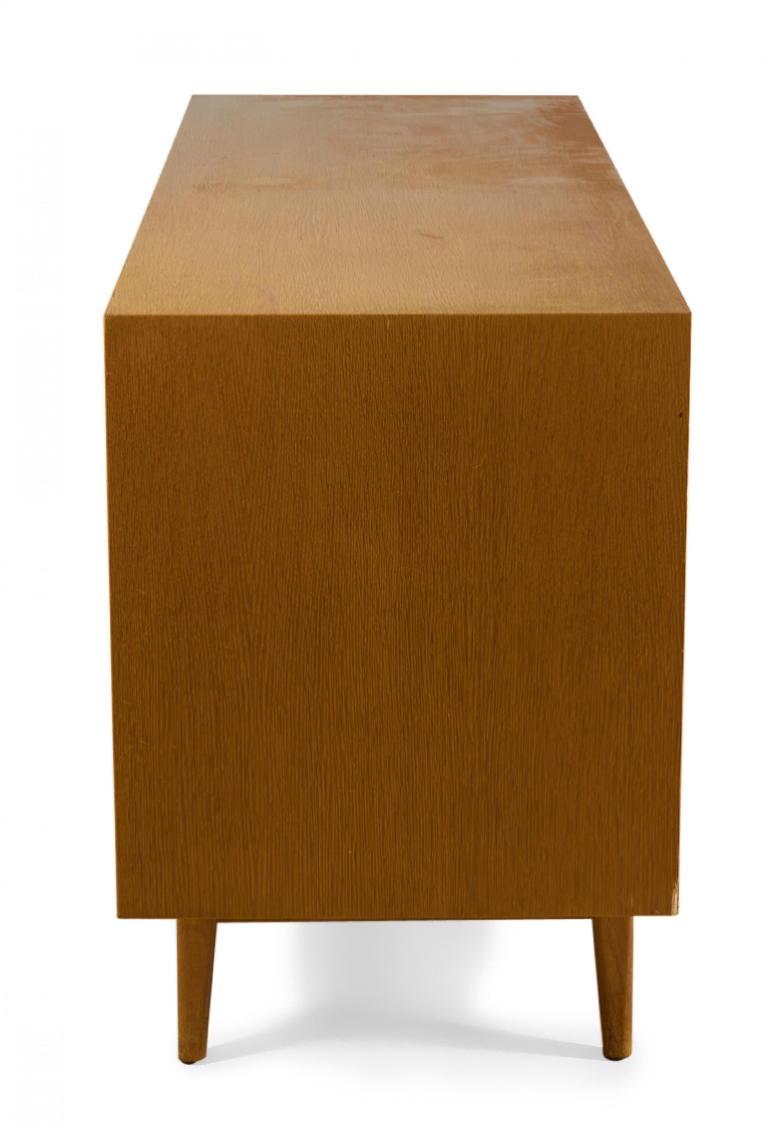 Dänisches Sideboard / Server aus blonder Eiche aus der Jahrhundertmitte mit drei zentralen Schubladen mit schrägen Holzschubladengriffen, die auf jeder Seite von zwei Schränken mit einem verstellbaren Regal in einem Gehäuse aus blonder Eiche auf