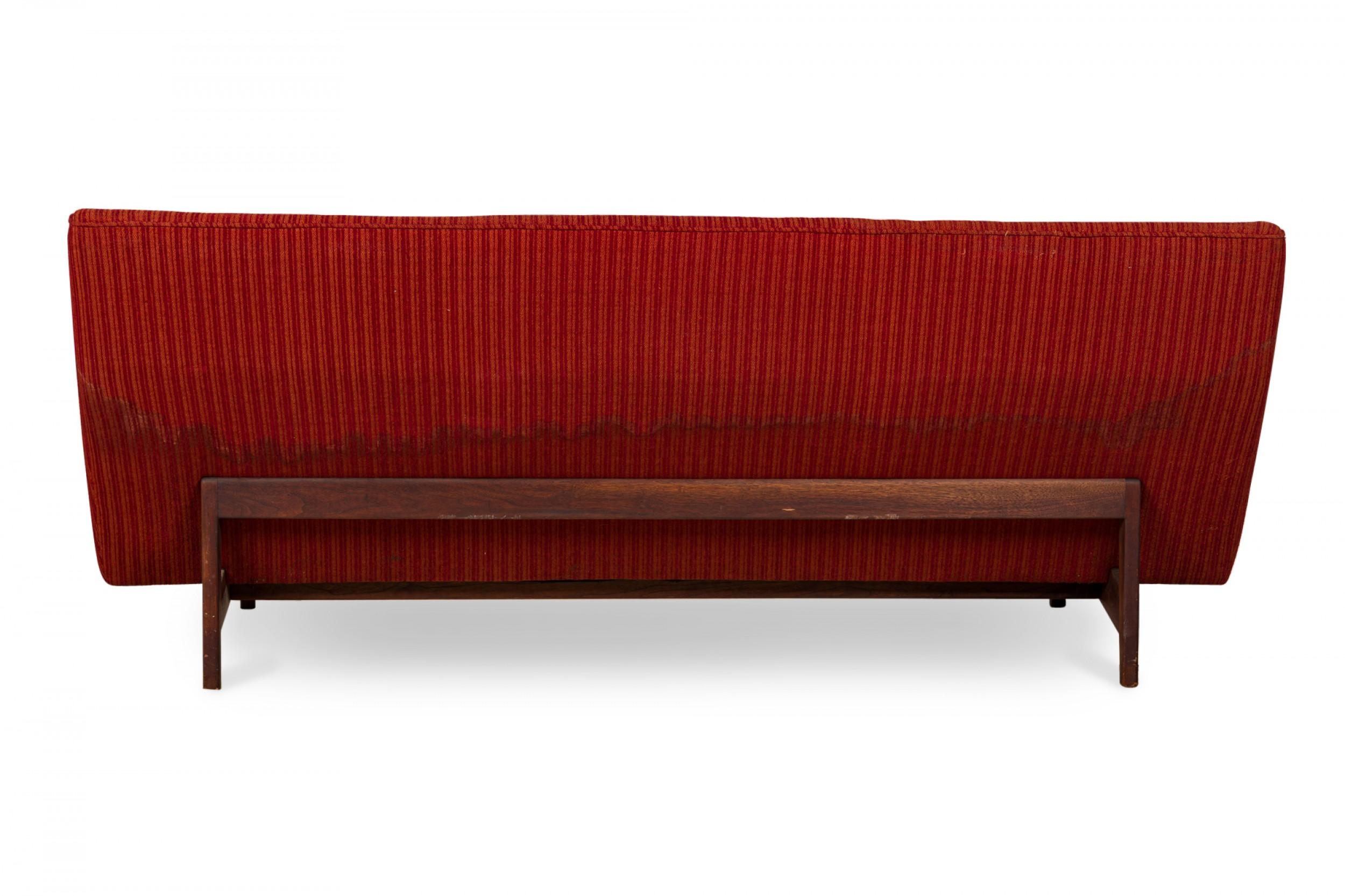 Divano danese del Mid-Century con braccioli angolati, schienale curvo e tappezzeria a righe rosse e arancioni con dettagli a bottoni, che poggia su una base in noce con quattro gambe quadrate affusolate. (JENS RISOM)

Tappezzeria usurata, macchiata