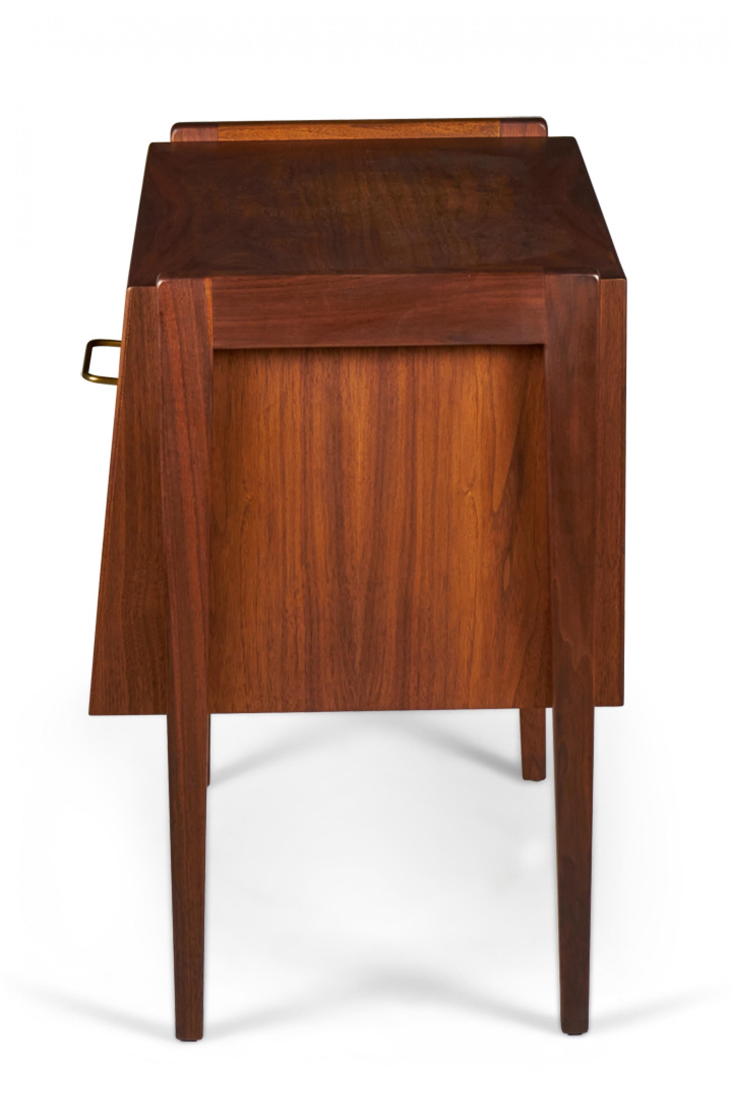 Danish Mid-Century walnut bedside table / commode with a bottom cabinet with a fall-front drawer and brass drawer pull with an open compartment above with four dowel legs. (JENS RISOM)
