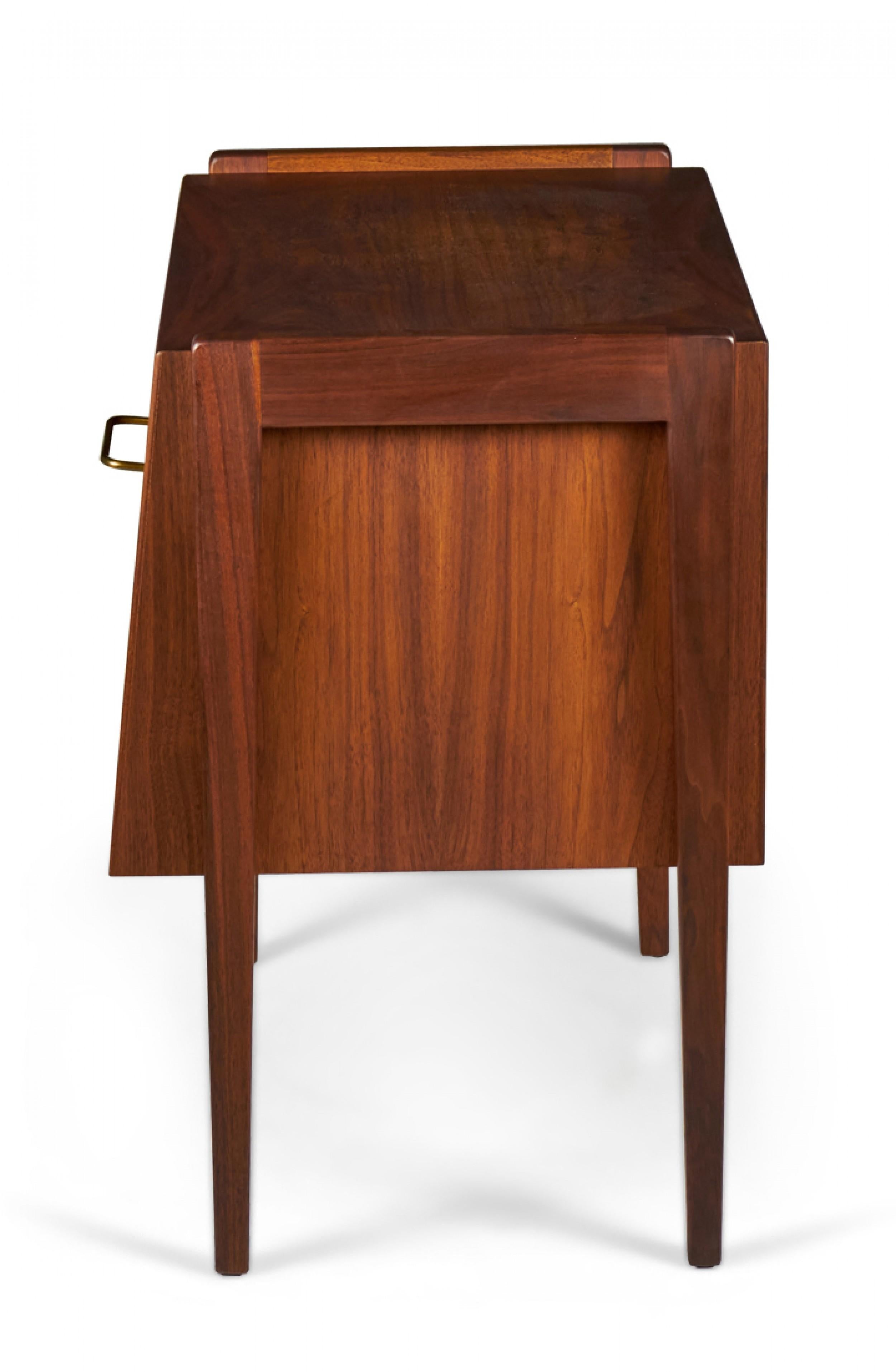 Table de chevet / commode danoise du milieu du siècle en noyer avec un meuble inférieur avec un tiroir à façade rabattable et une poignée à tiroir en laiton avec un compartiment ouvert au-dessus avec quatre pieds en forme de cheville. (JENS RISOM).