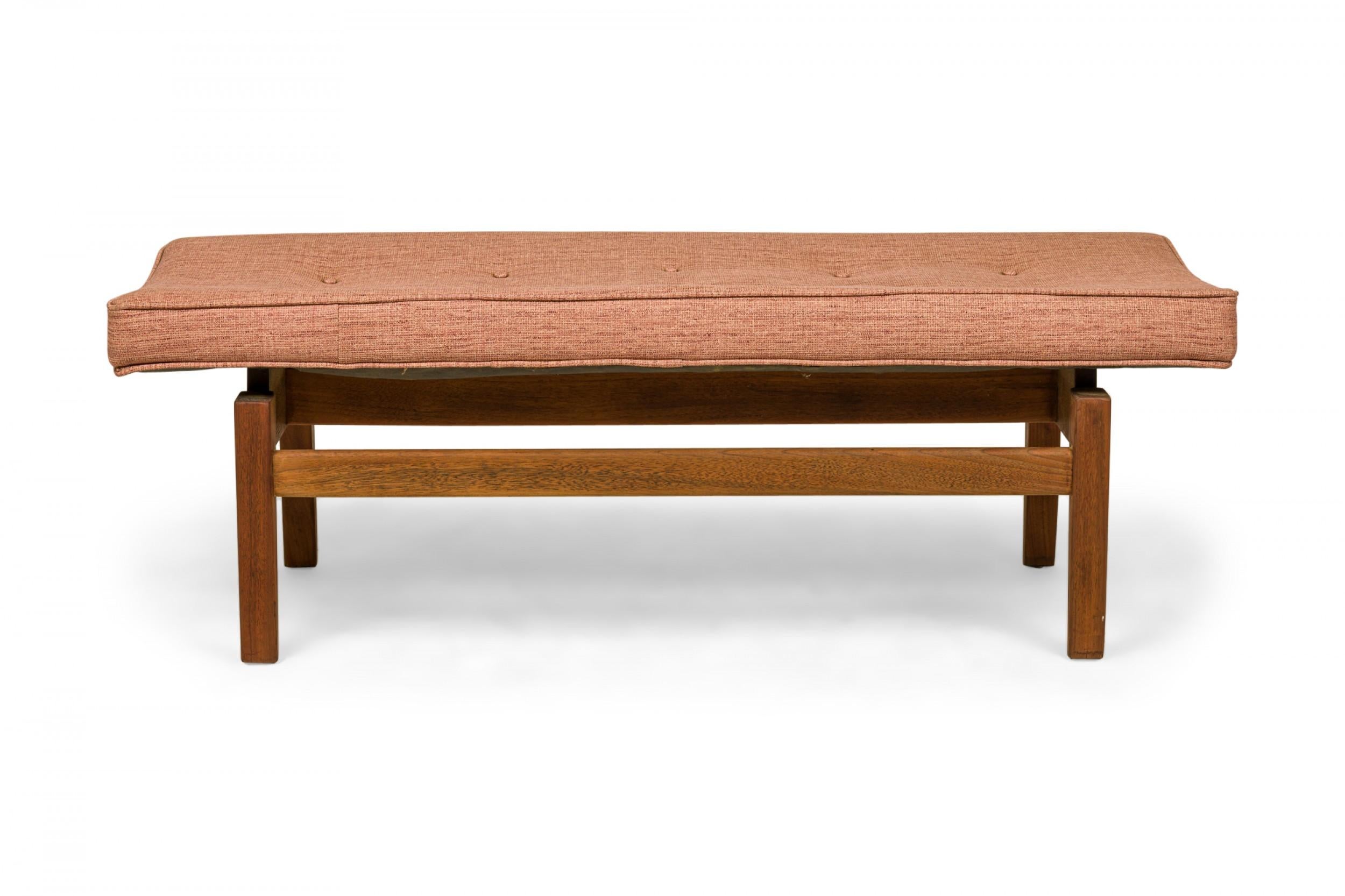 Danish Mid-Century floating bench with a textured rose pink upholstered seat resting on a walnut frame. (JENS RISOM).
 