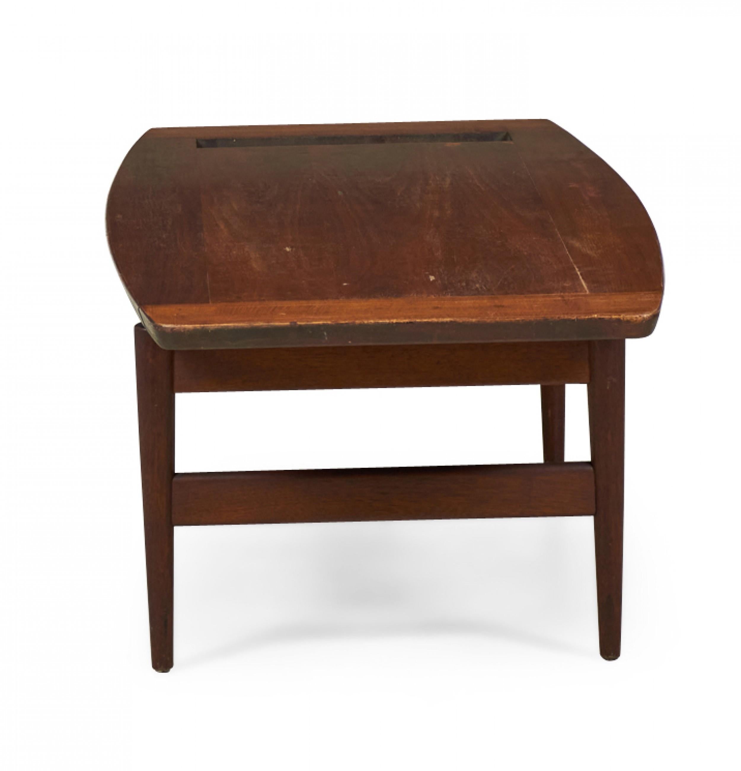 Danish Mid-Century walnut coffee table with a rectangular top with tapered edges and a rectangular cutout on one side resting on a stretcher base with built-in magazine rack and four tapered legs. (JENS RISOM) (Similar table: DUF0098B)
