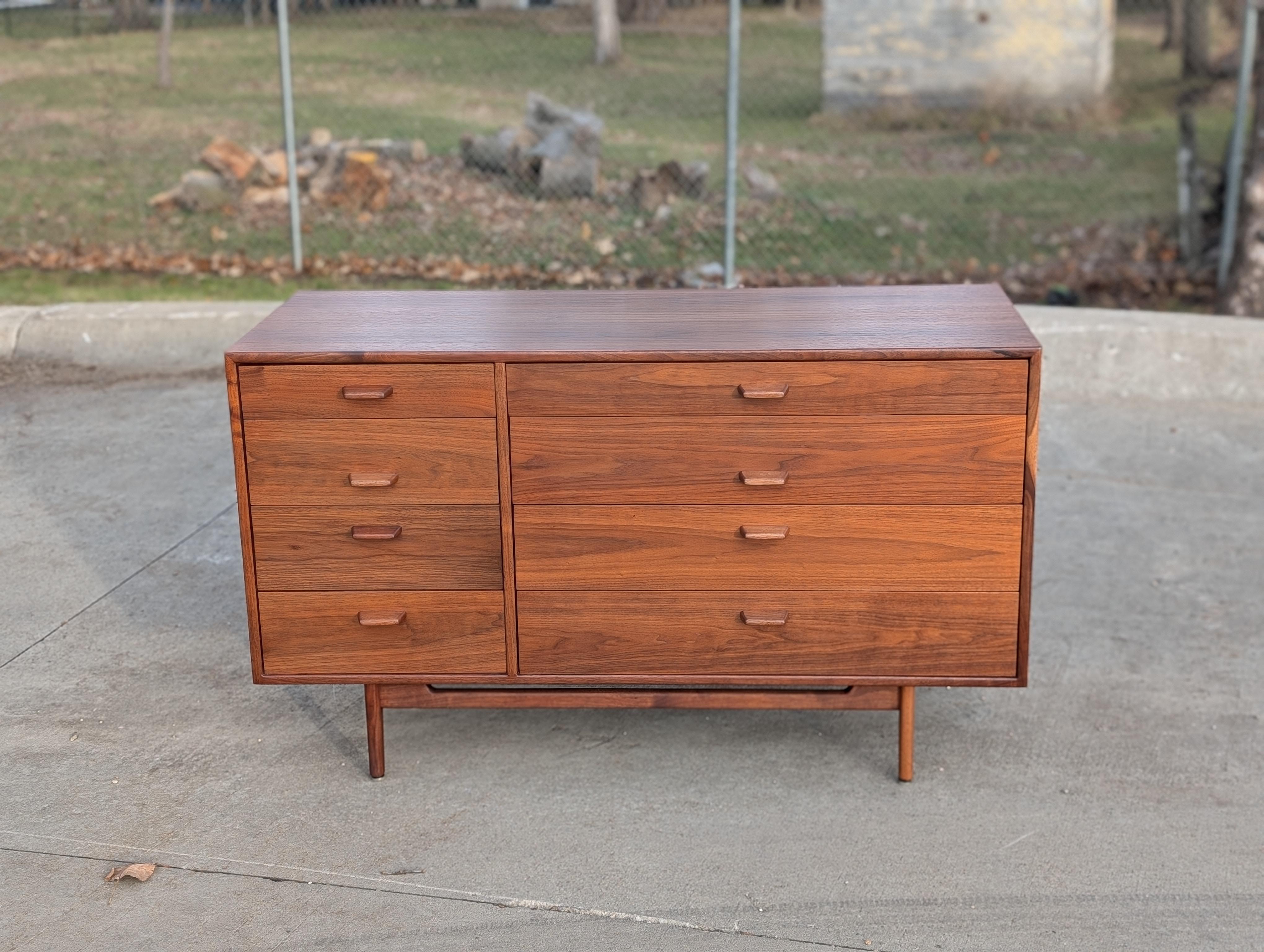 Walnut dresser with 8 drawers designed by Jens Risom.

Four narrow drawers on left, flanked by wider drawers on right.

Top drawer includes brass push button latch and hinges, allows the front to be folded down and used a writing surface.

Good