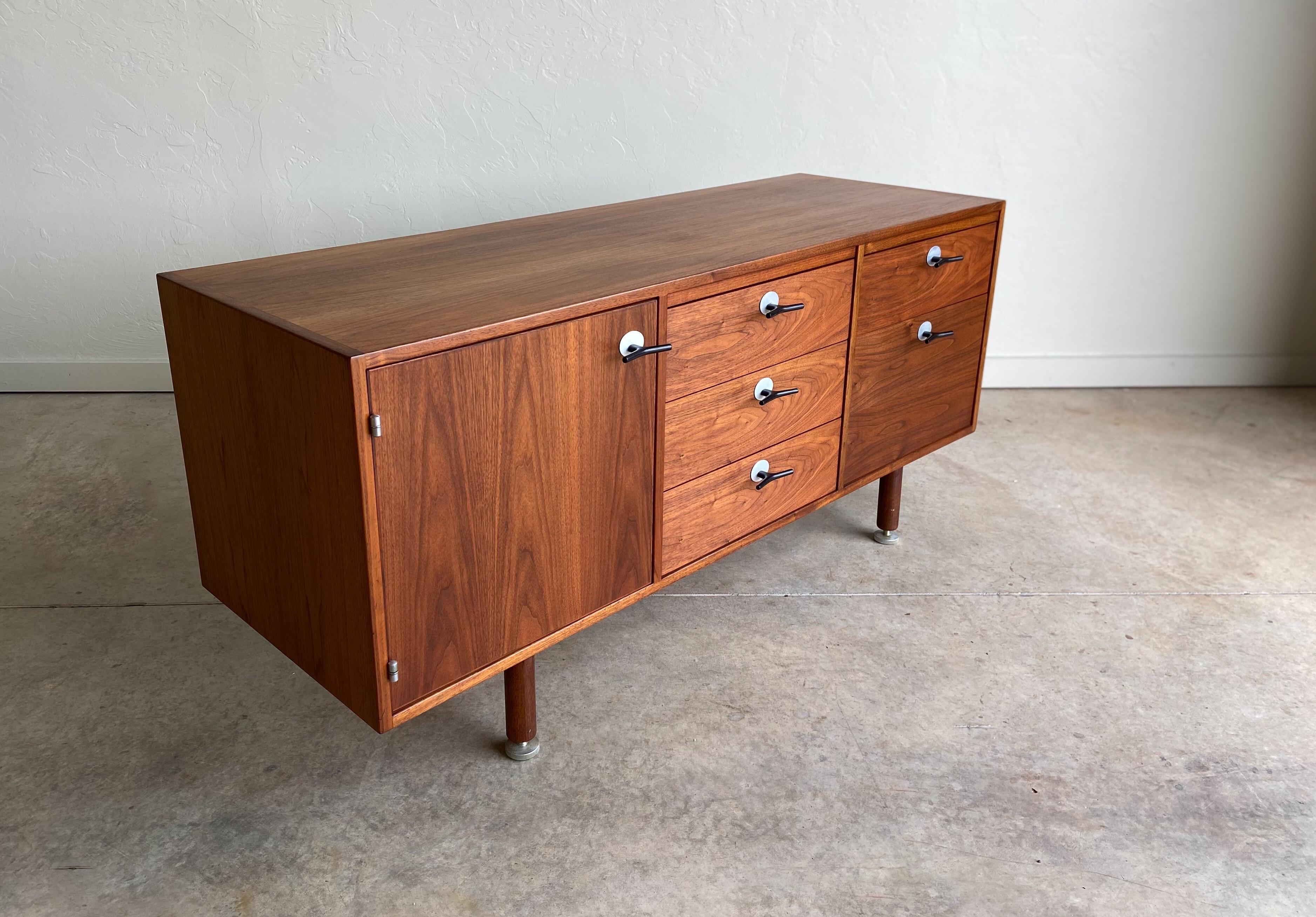 A smaller scale credenza designed by Jens Risom for Jens Risom Design Inc. Features amazing walnut grain that is finished on all sides. This version has the desirable and more rare aluminum “Y” pulls. Provides ample storage with various drawer