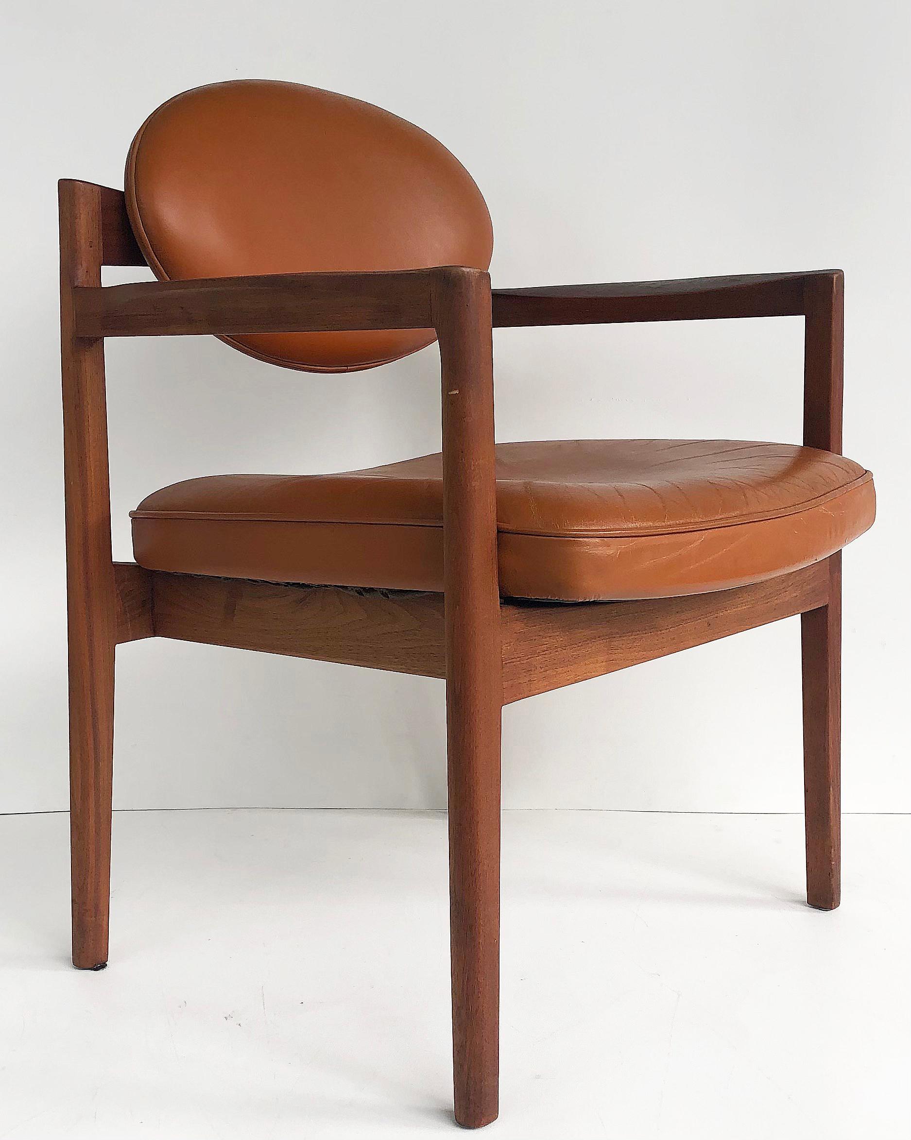 Offered for sale is an original pair of Jen Risom Design oiled walnut and leather upholstered armchairs. The chairs have upholstered oval backs on a sculptural walnut base, c.1965. A re-edition of the chair is currently being retailed at John