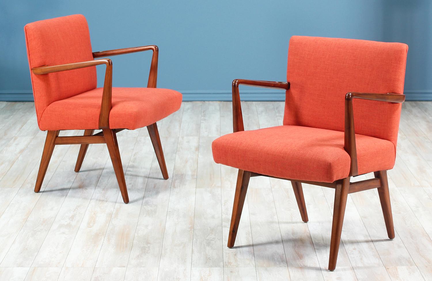 Pair of easy chairs designed by Jens Risom for Knoll Inc. in the United States circa 1950’s. These stylish chairs feature a solid walnut wood frame with tapered legs and carved angled arm-rests. The seats have been recently upholstered in a soft