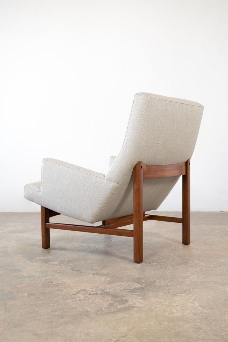 Low-slung Jens Risom lounge chair floating in a solid walnut cradle frame. This chair is very architectural in appearance with its tight lines and taut upholstery but is also very comfortable. It has been restored to the highest possible standard