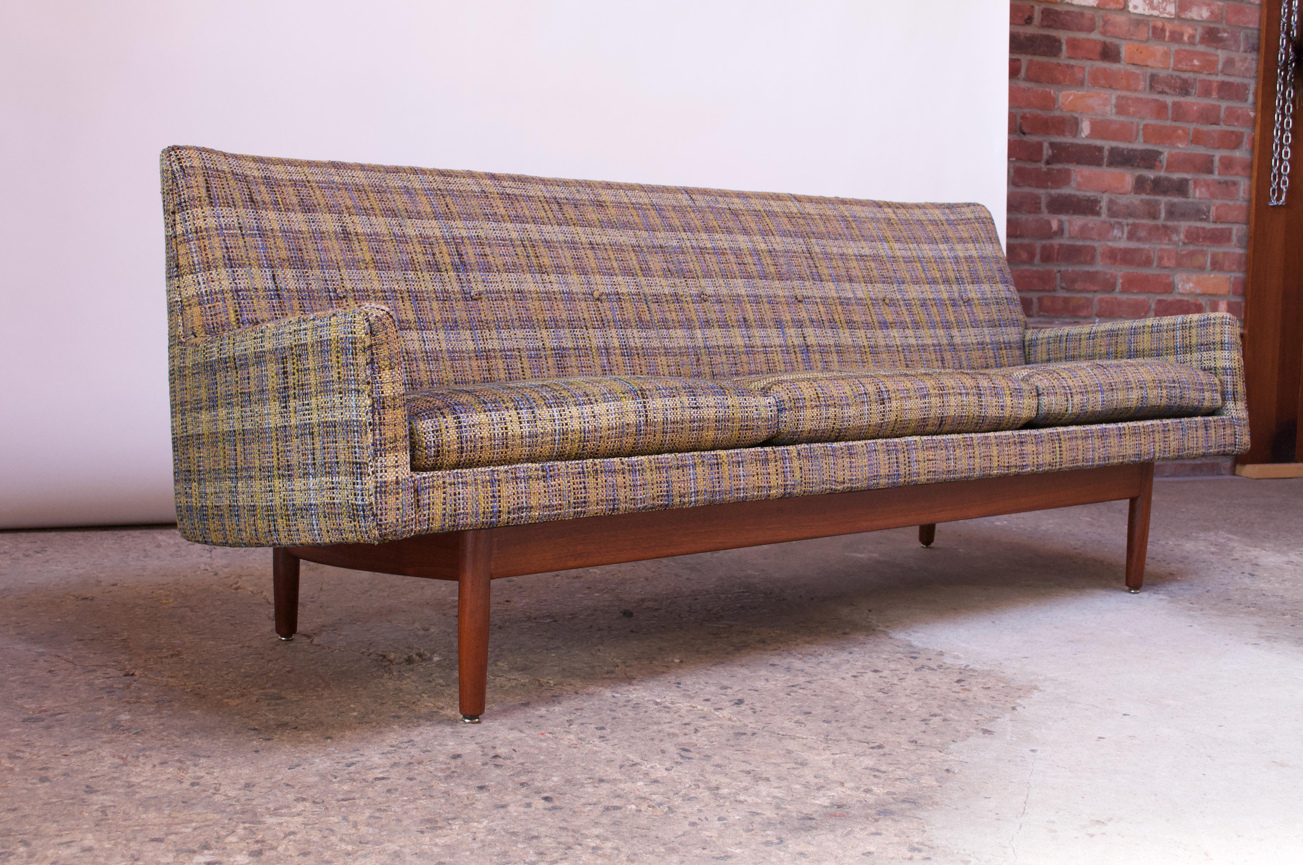 Handsome three-seat sofa designed by Jens Risom for Risom Design in the 1950s. Clean, sharp lines with a decorative button-tufted back detail. Sofa is supported by a sculptural walnut base. The plaid tweed upholstery in an attractive weave of navy,