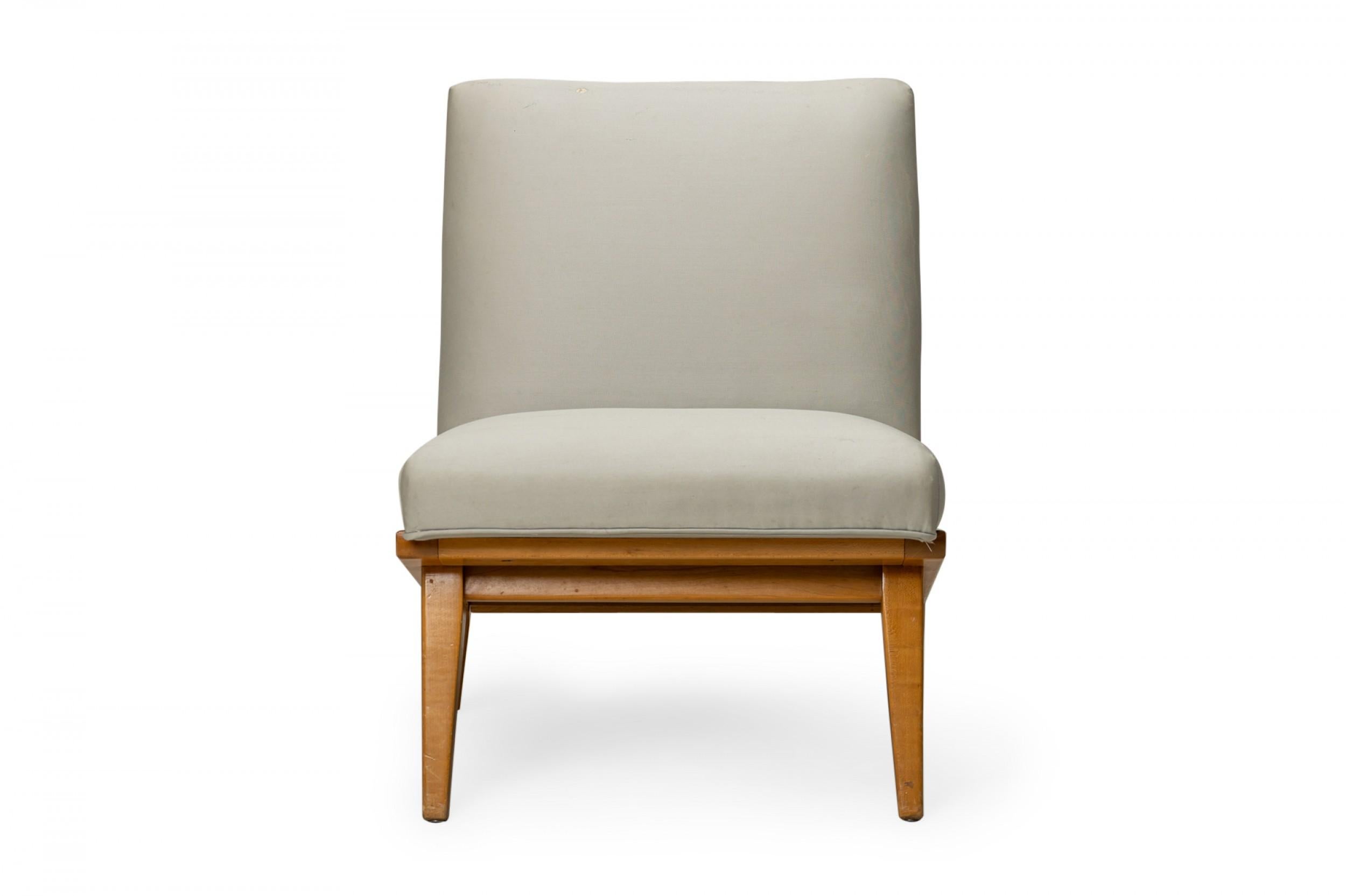Mid-Century Modern slipper / side chair with light gray sateen fabric upholstery, resting on an angled blonde wood base with angled and tapered legs. (JENS RISOM FOR KNOLL)(Similar pieces: DUF0453-DUF0455)

