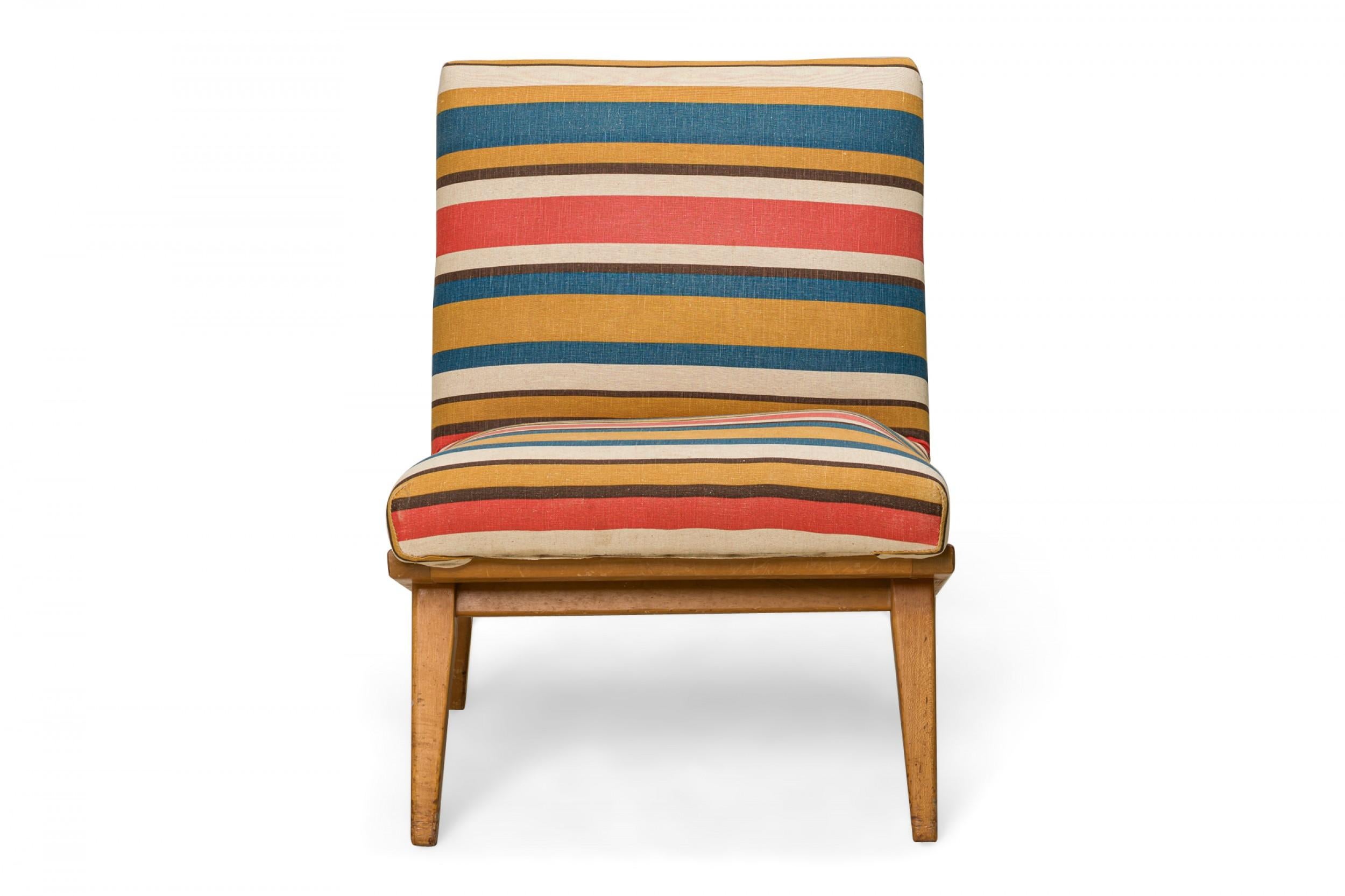 Mid-Century Modern slipper / side chair with red, blue, yellow, and beige striped fabric upholstery, resting on an angled blonde wood base with angled and tapered legs. (JENS RISOM FOR KNOLL)(Similar pieces: DUF0452-DUF0454)
 