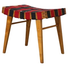 Taburete de centro inspirado en Jens Risom con cinchas negras y rojas y estructura de madera