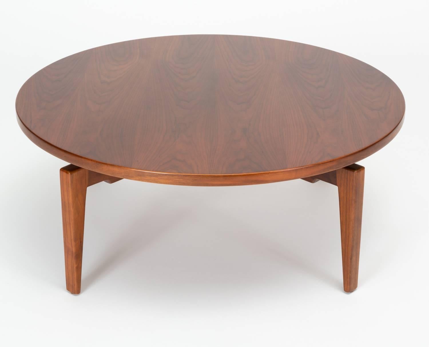 A 1958 design for a large round walnut coffee table by Jens Risom that rotates on a central mechanism for a “Lazy Susan” effect. There is a hidden wheel underneath the table that can be adjusted to increase resistance and act as a brake. The four