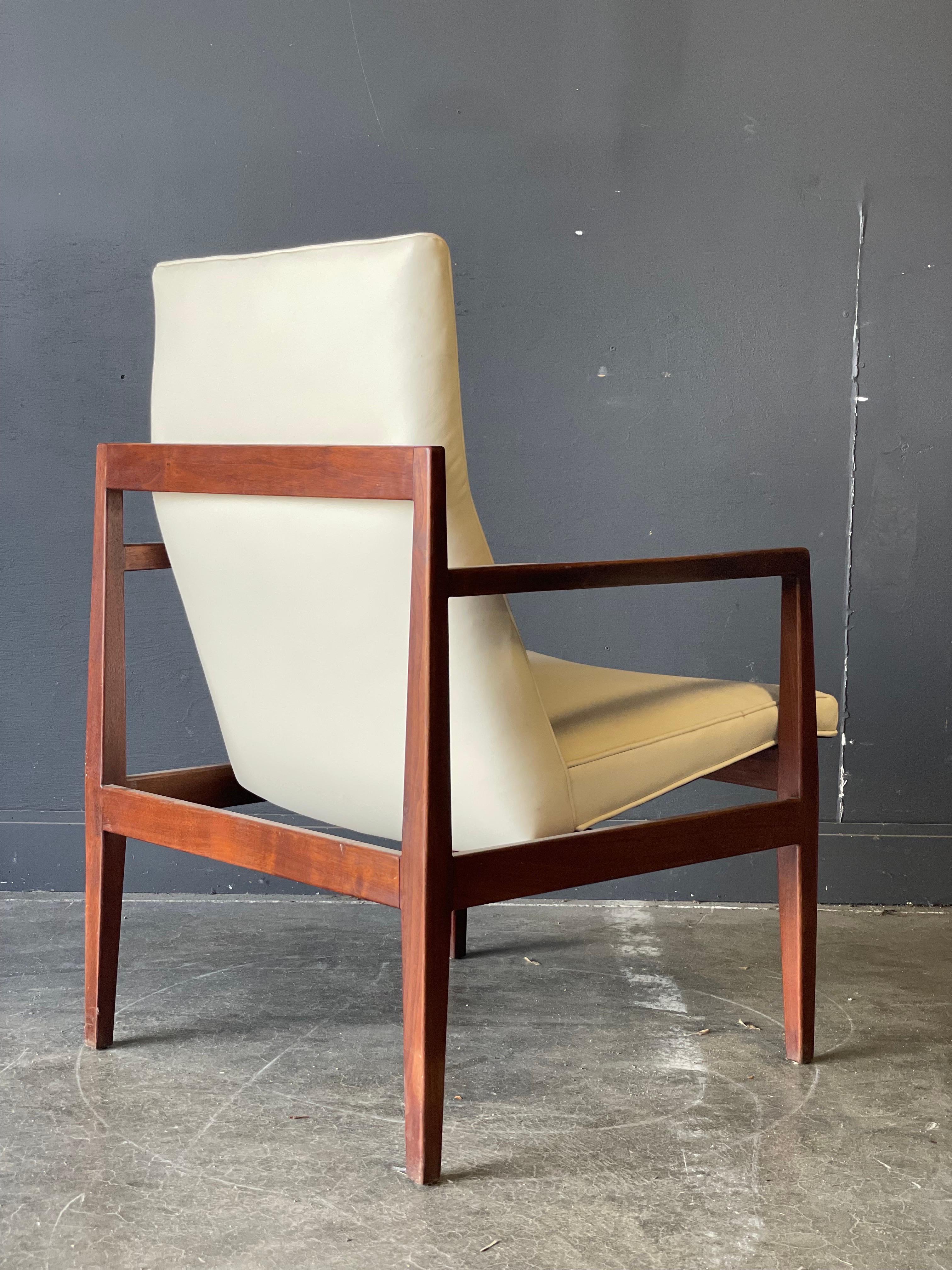 A classic Jens Risom mid century open arm chair circa 1965. Upholstered with a white leather seat. Beautiful carved walnut is ergonomically designed for your comfort and visual pleasure.
