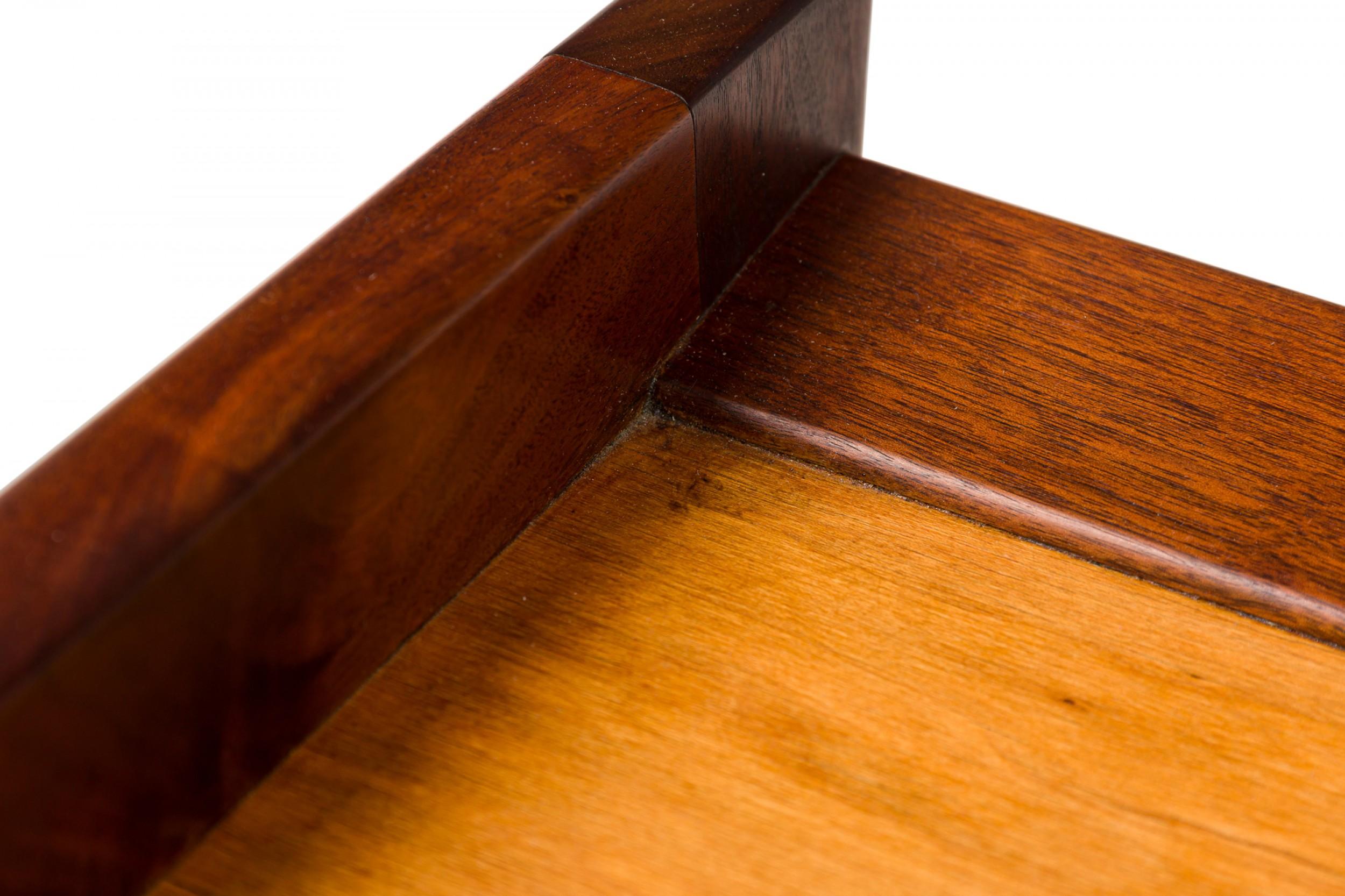 Mid-Century Danish walnut ottoman with a rectangular angled framework, raised edges on opposing sides which enclose an inlaid center and splayed, tapered legs. (JENS RISOM)

Condition: Good; Wear consistent with age and use