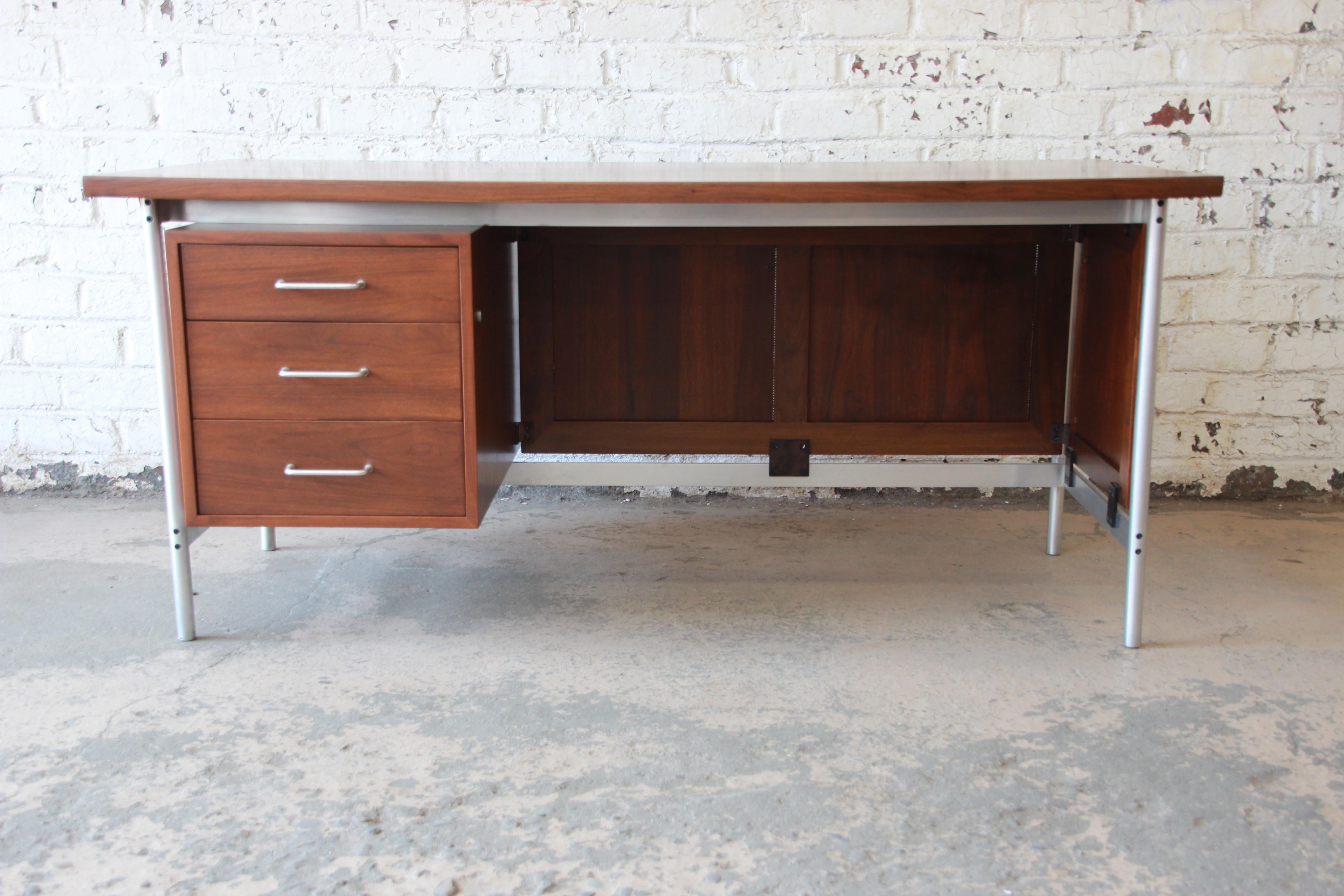An exceptional Mid-Century Modern executive desk designed by Jens Risom for Jens Risom Design, Inc. This rare desk features gorgeous walnut wood grain and sleek midcentury design. It has an exposed steel frame and a unique caned privacy panel. It
