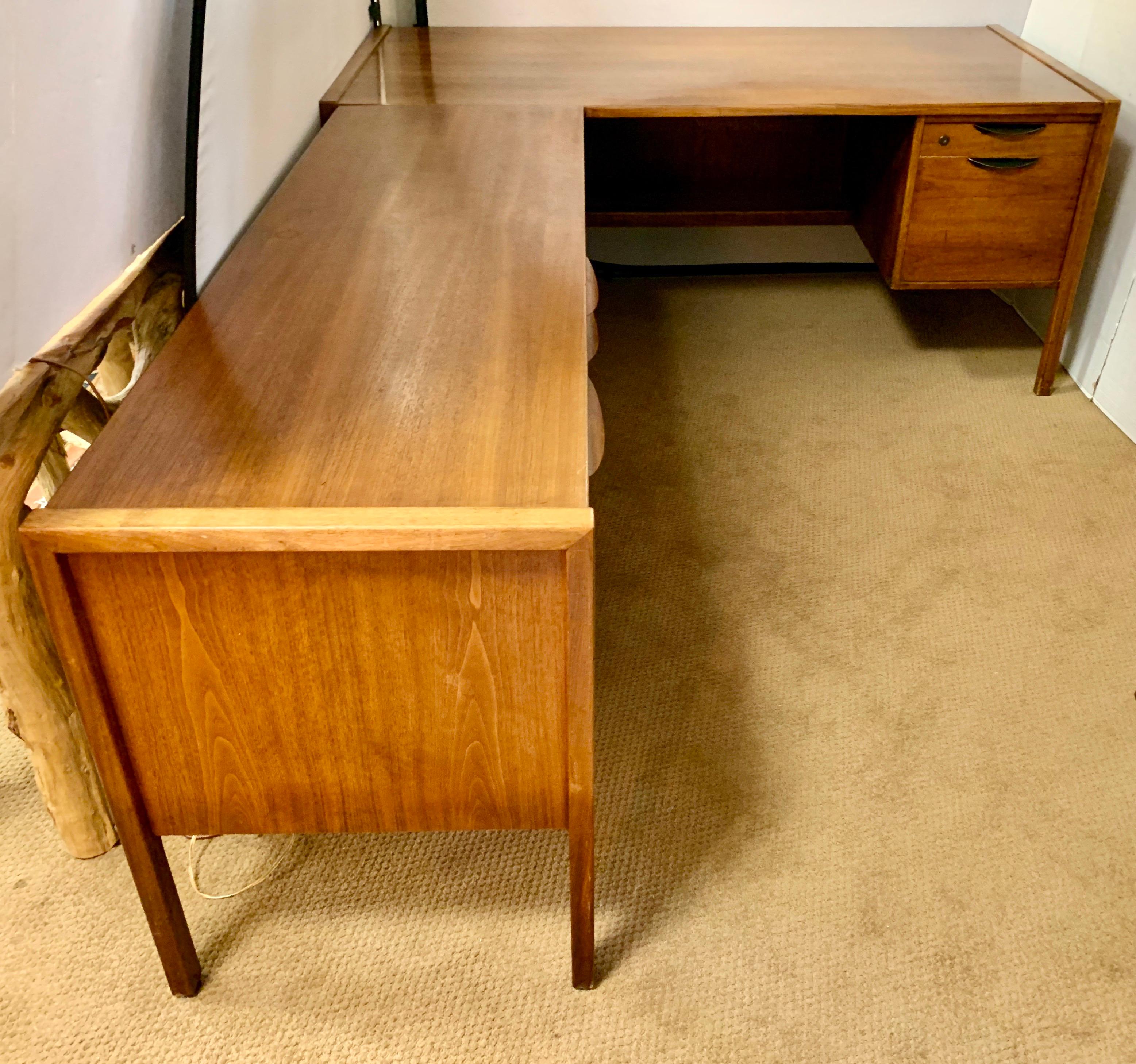An exceptional Mid-Century Modern two piece walnut executive desk designed by Jens Risom. The desk features gorgeous walnut wood grain and sleek Minimalist design. It offers exceptional storage with multiple drawers. The original Jens Risom label is