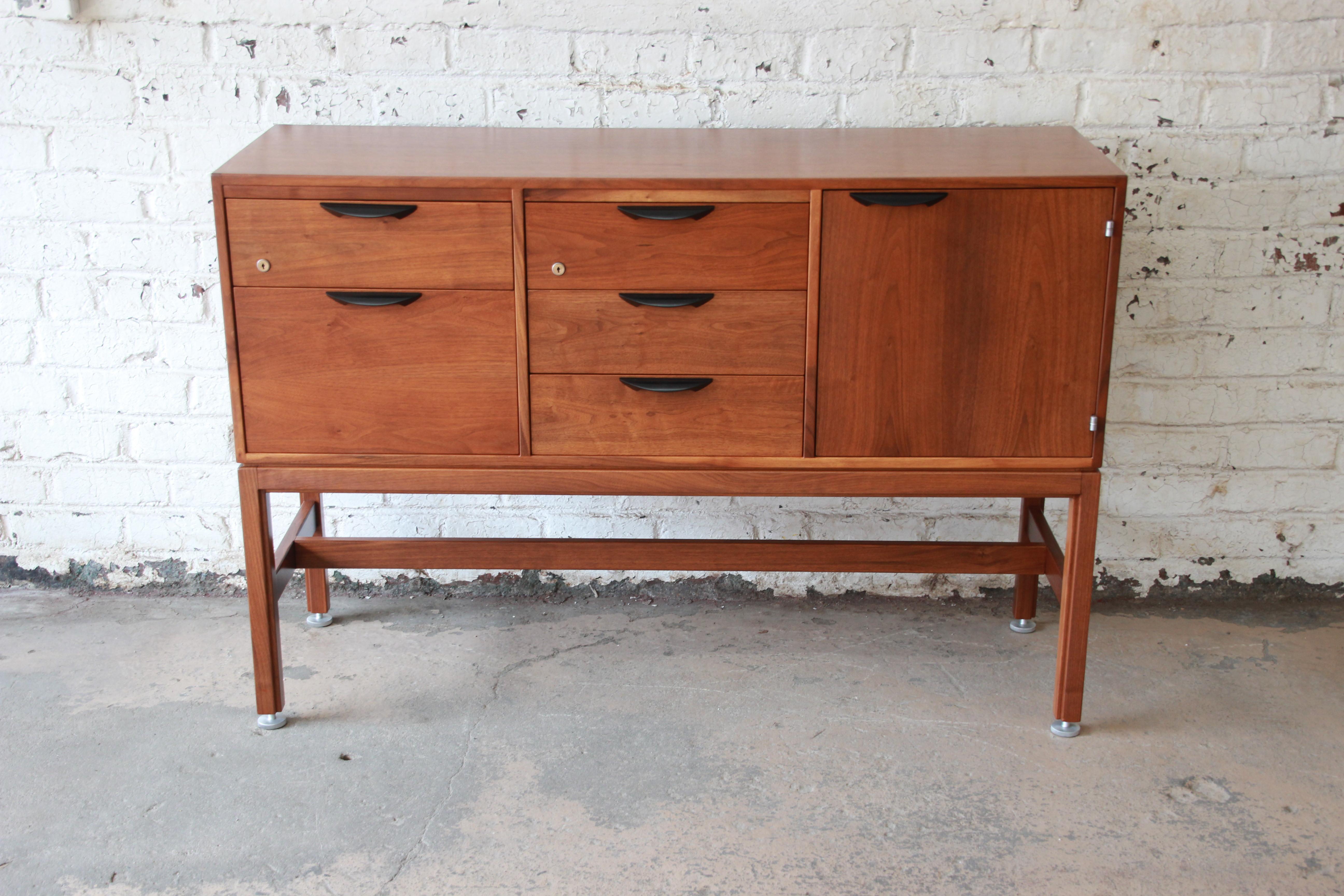 An exceptional solid walnut credenza designed by Jens Risom, circa 1960s. The credenza features gorgeous walnut wood grain and handsome sculpted ebonized drawer pulls. It offers ample room for storage with five deep drawers and a shelved cabinet