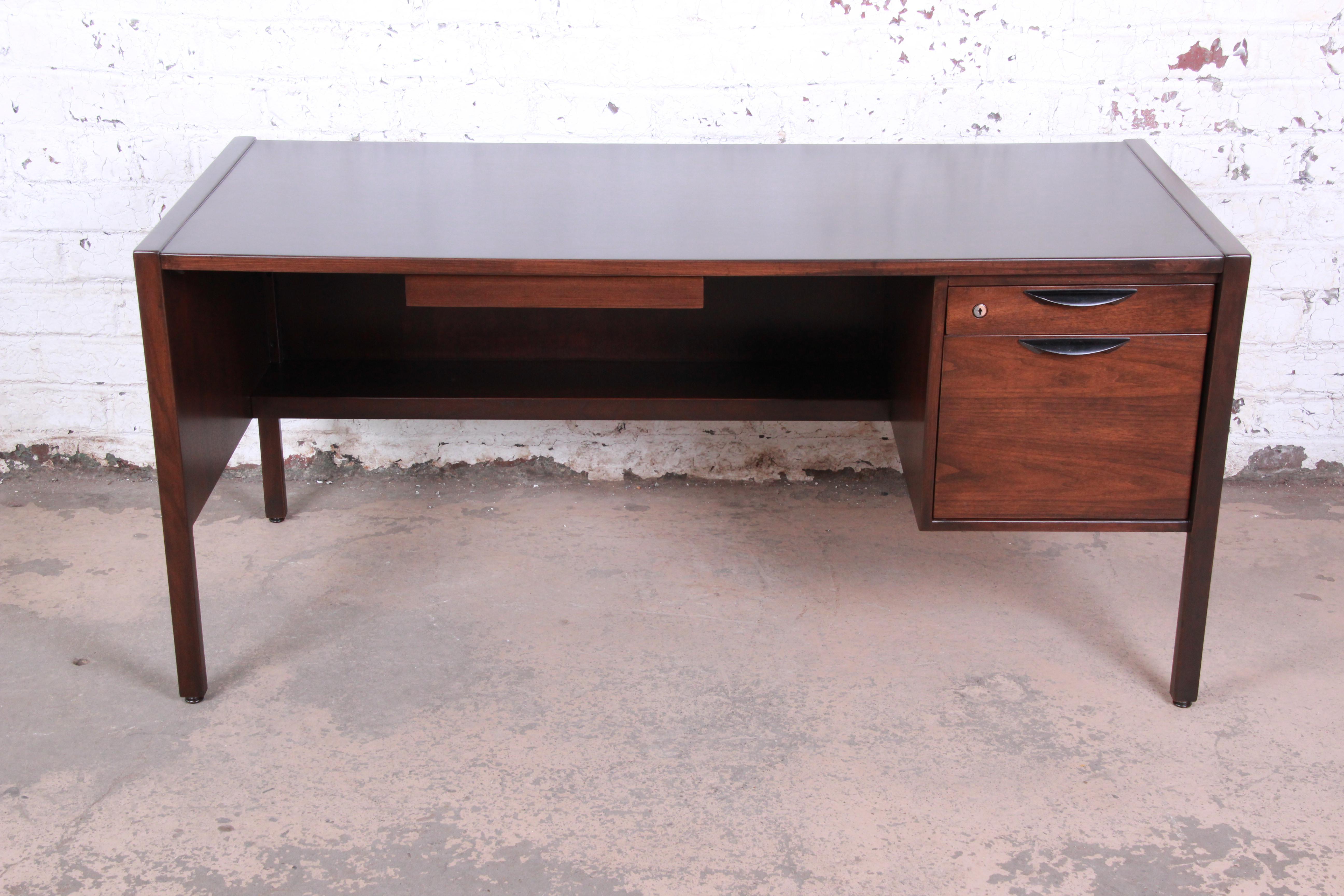 An exceptional Mid-Century Modern walnut executive desk designed by Jens Risom. The desk features gorgeous walnut wood grain and sleek Minimalist design. It offers good storage with three drawers. The desk is finished on all sides and could be used