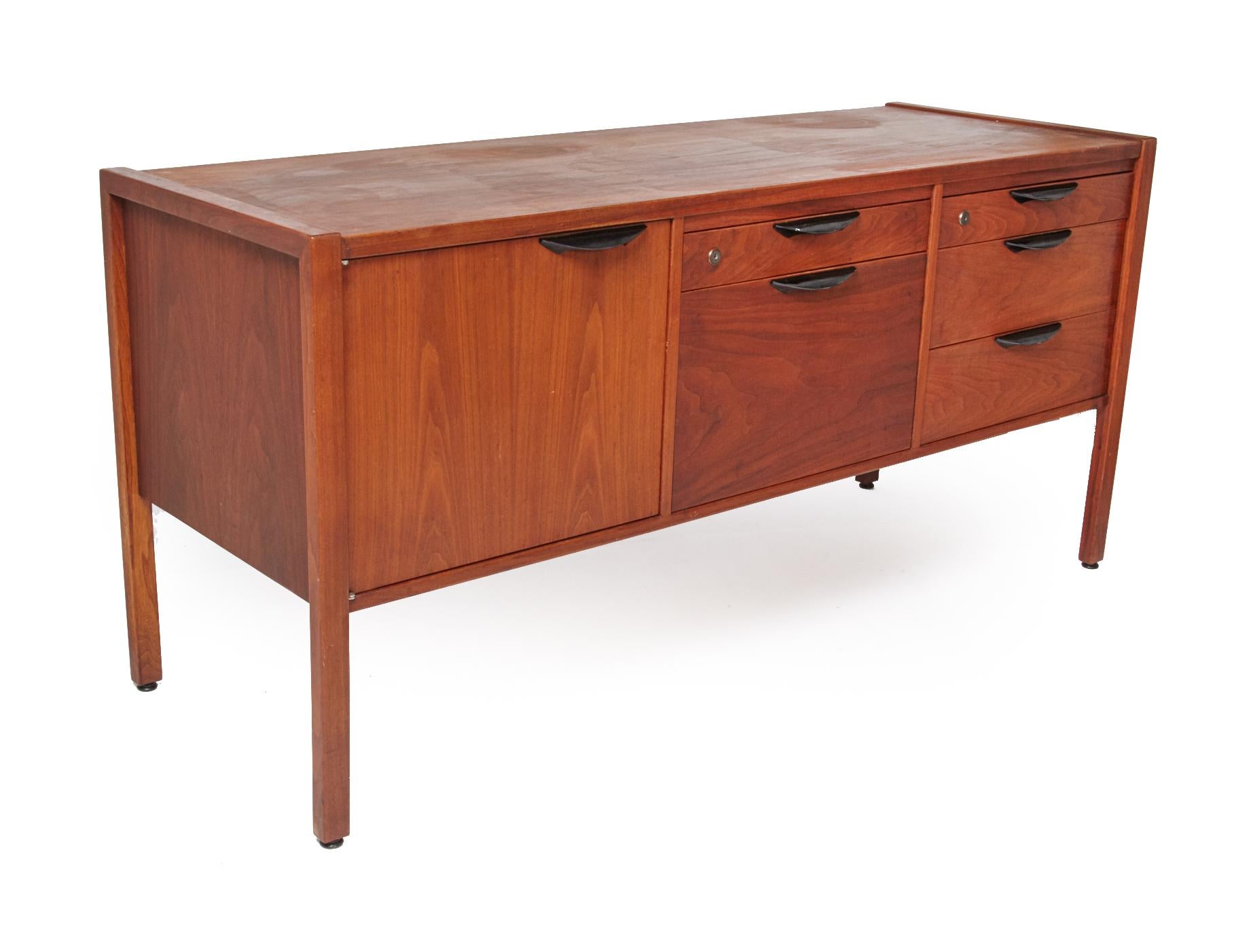 Nice walnut midcentury office / dining credenza by designer Jens Risom in excellent condition. Label is inside drawer. Piece has multiple drawers of various sizes including a file drawer at the center and a 2 shelf cupboard on the left. Drawer pulls