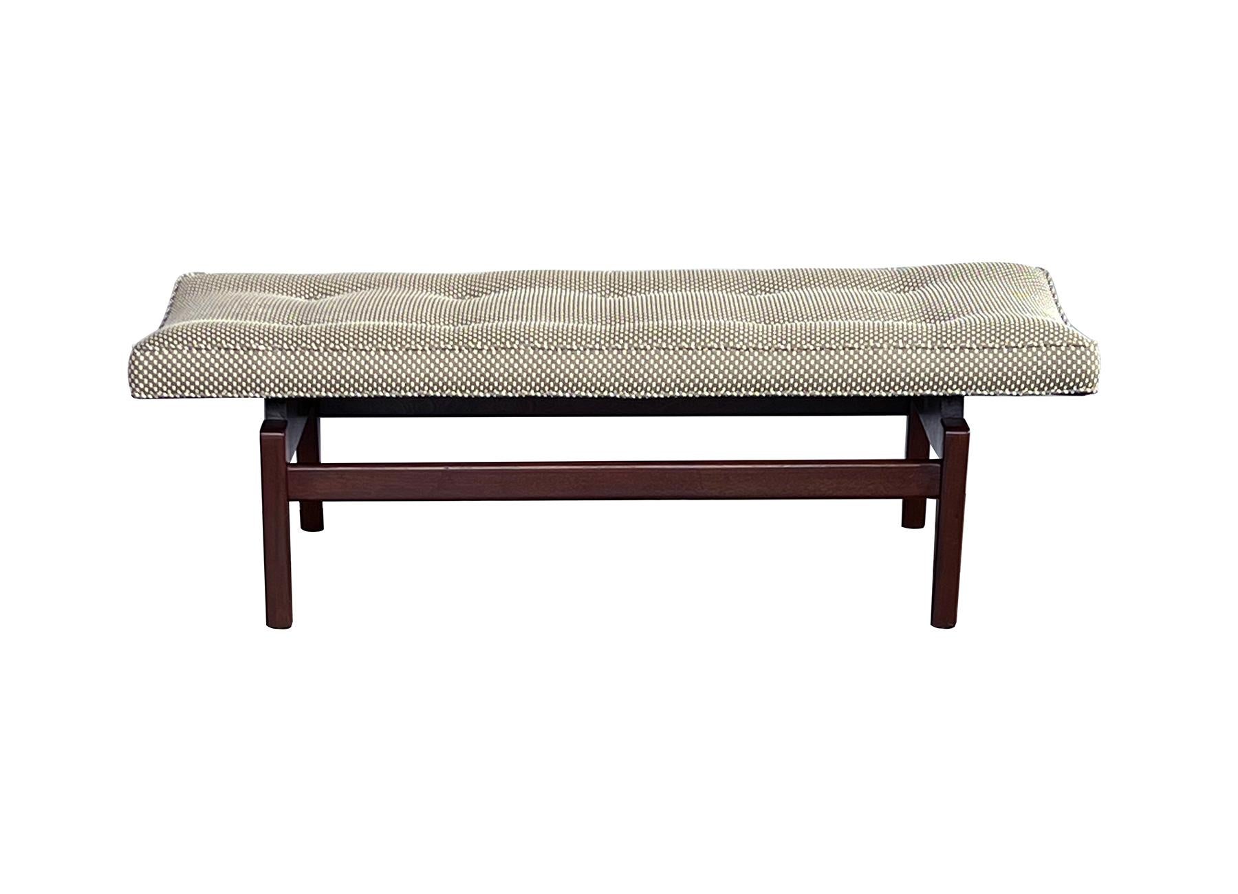 signed 1960s bench with floating rectangular upholstered seat resting on a walnut base with square-form tapering legs connected by two stretchers; makers label to inner stretcher; Jens Risom (1916-2016) was a Danish American furniture designer. An