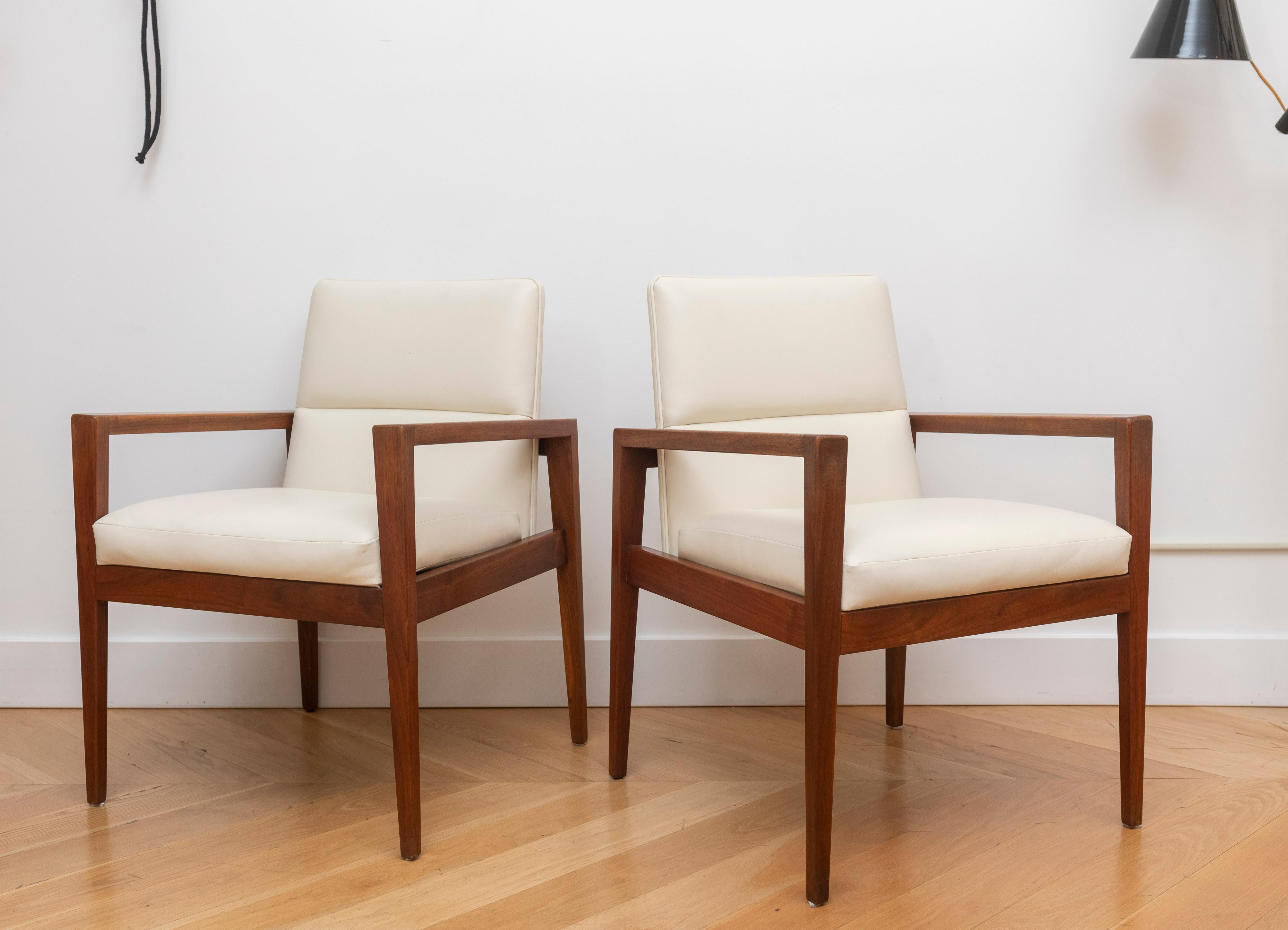 Pair of Jens Risom 1960s arm chairs. These examples have newly finished solid walnut frames with subtly tapered arms and have bean recently upholstered in a soft off-white leather.