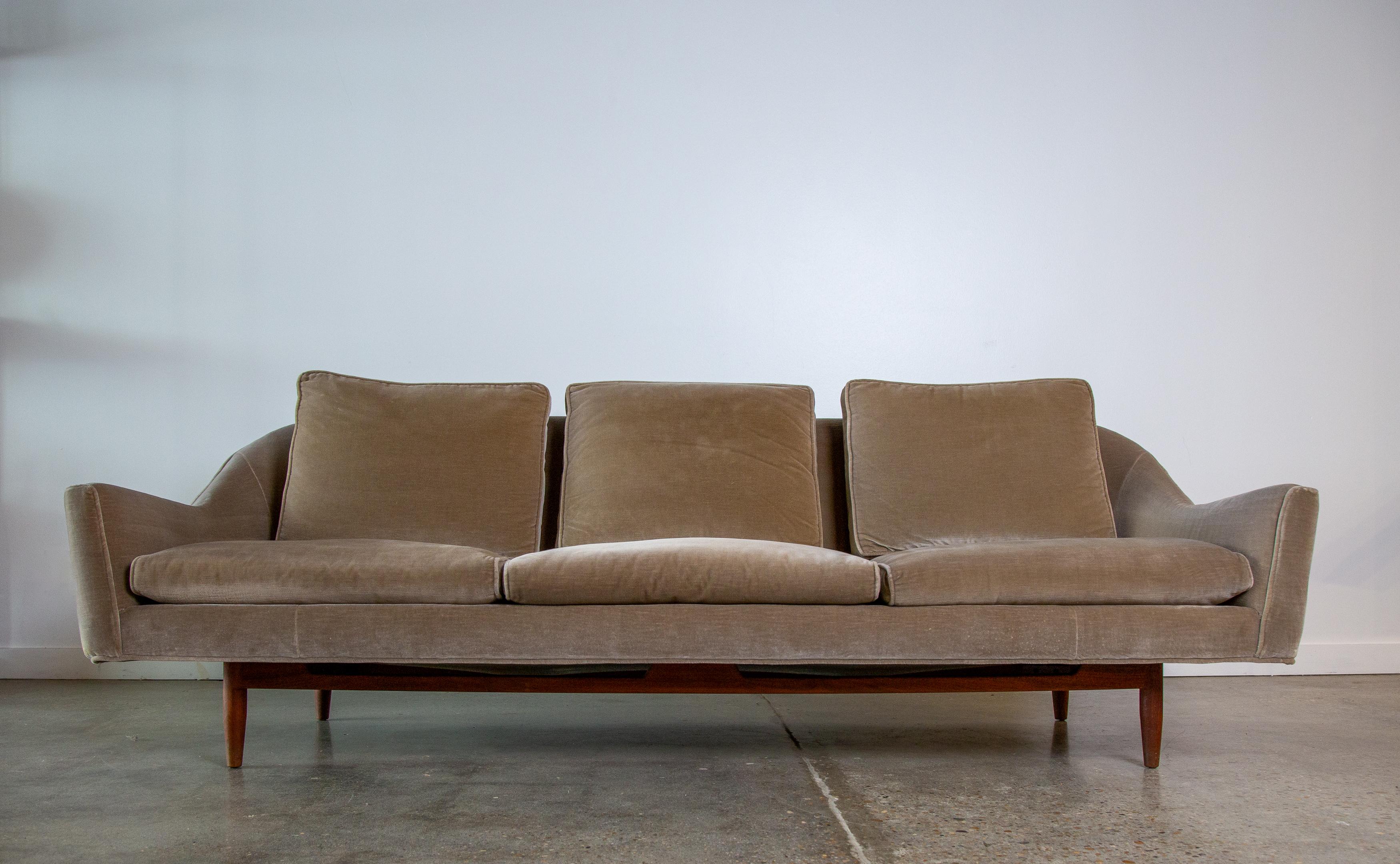 Uncommon Jens Risom Model 2516 sofa with a curvaceous back and sculptural walnut base.  The sides of the base with subtle bow tie shape, cutouts in the front of the frame lend to the allusion of floating.  The front with a generous cantilever off