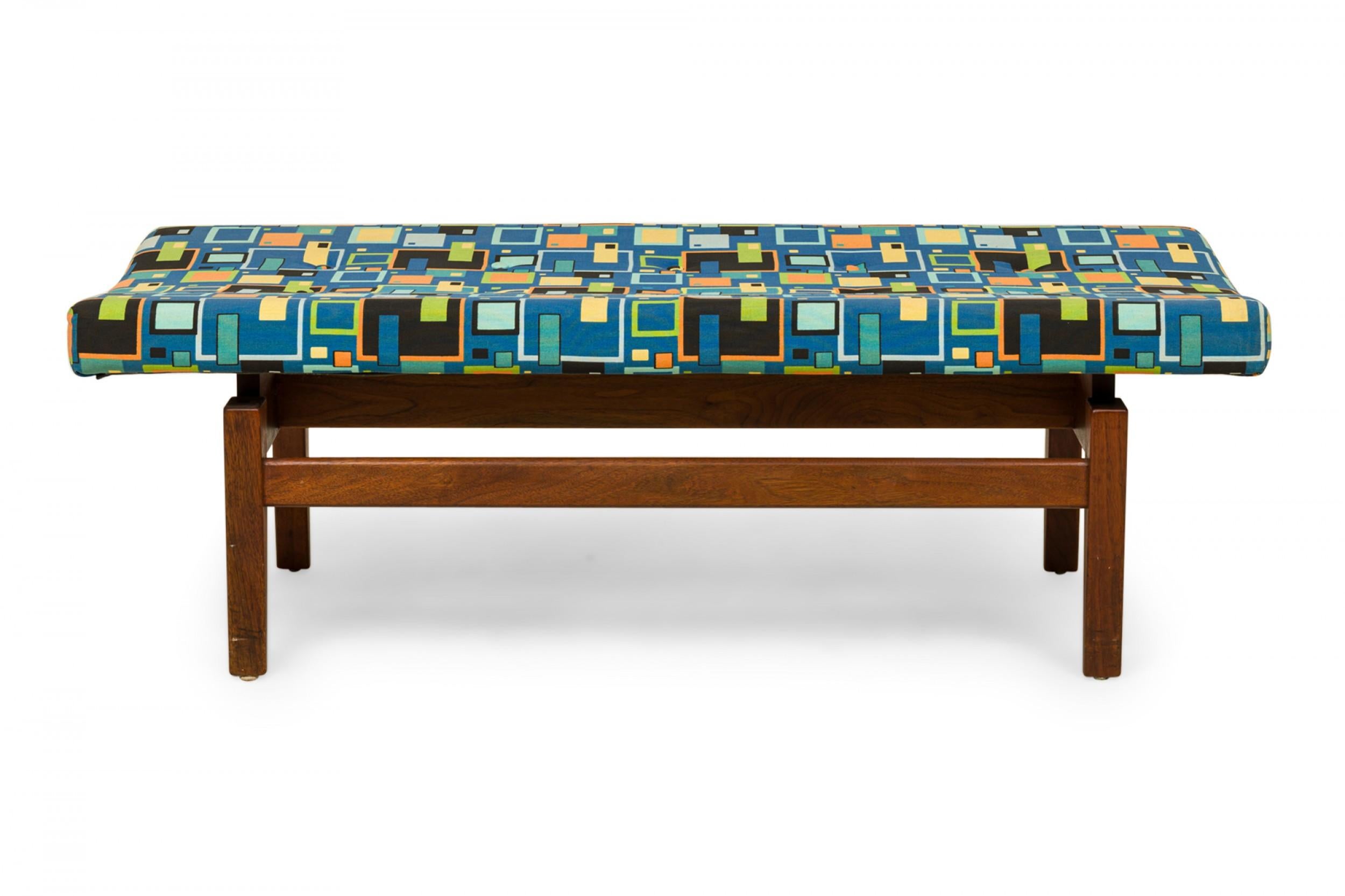 Danish Mid-Century rectangular floating bench with a geometrically patterned blue, green, and orange fabric upholstered seat resting on a wooden floating frame base. (JENS RISOM).
 