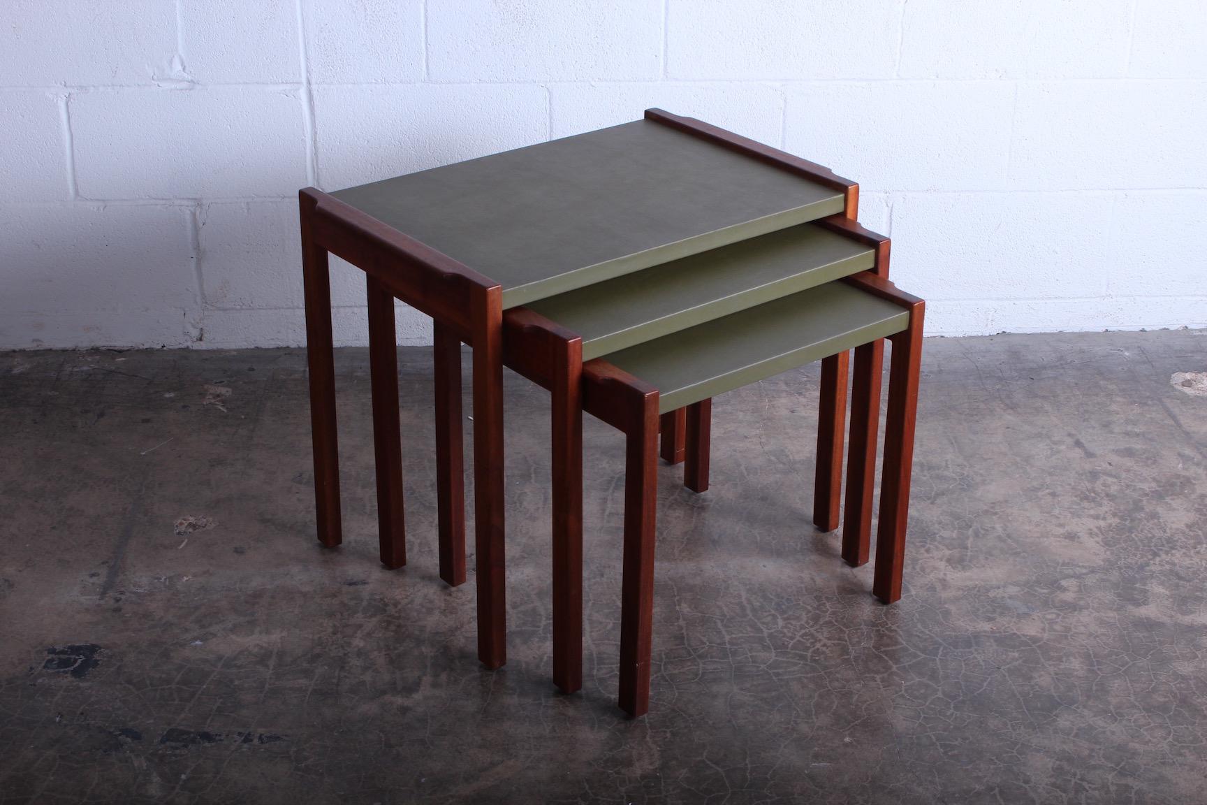 A set of three walnut nesting tables with green vinyl tops. Designed by Jens Risom.