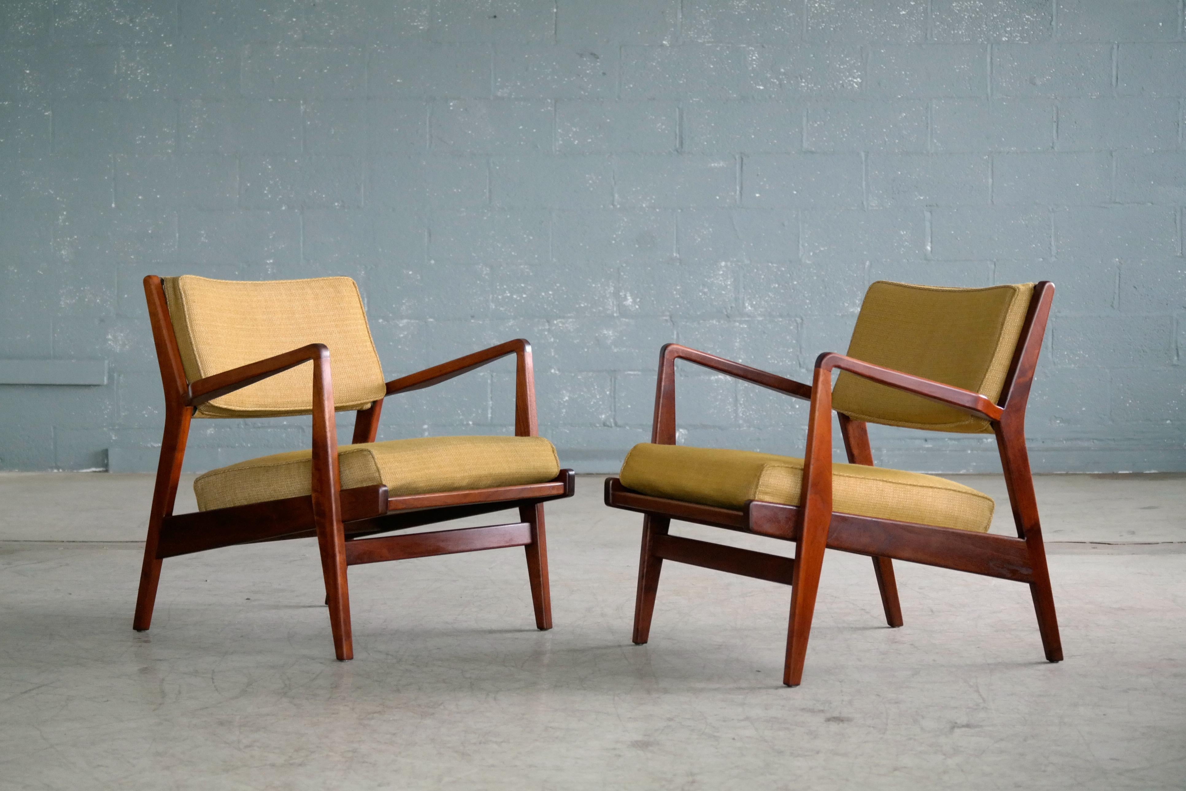 Superb pair of Jens Risom lounge chairs in walnut from the mid-1960s. Beautiful original condition with the wooden frames in mint condition showing great color and grain and the cushions showing minor wear and some hardening of the foam. We do