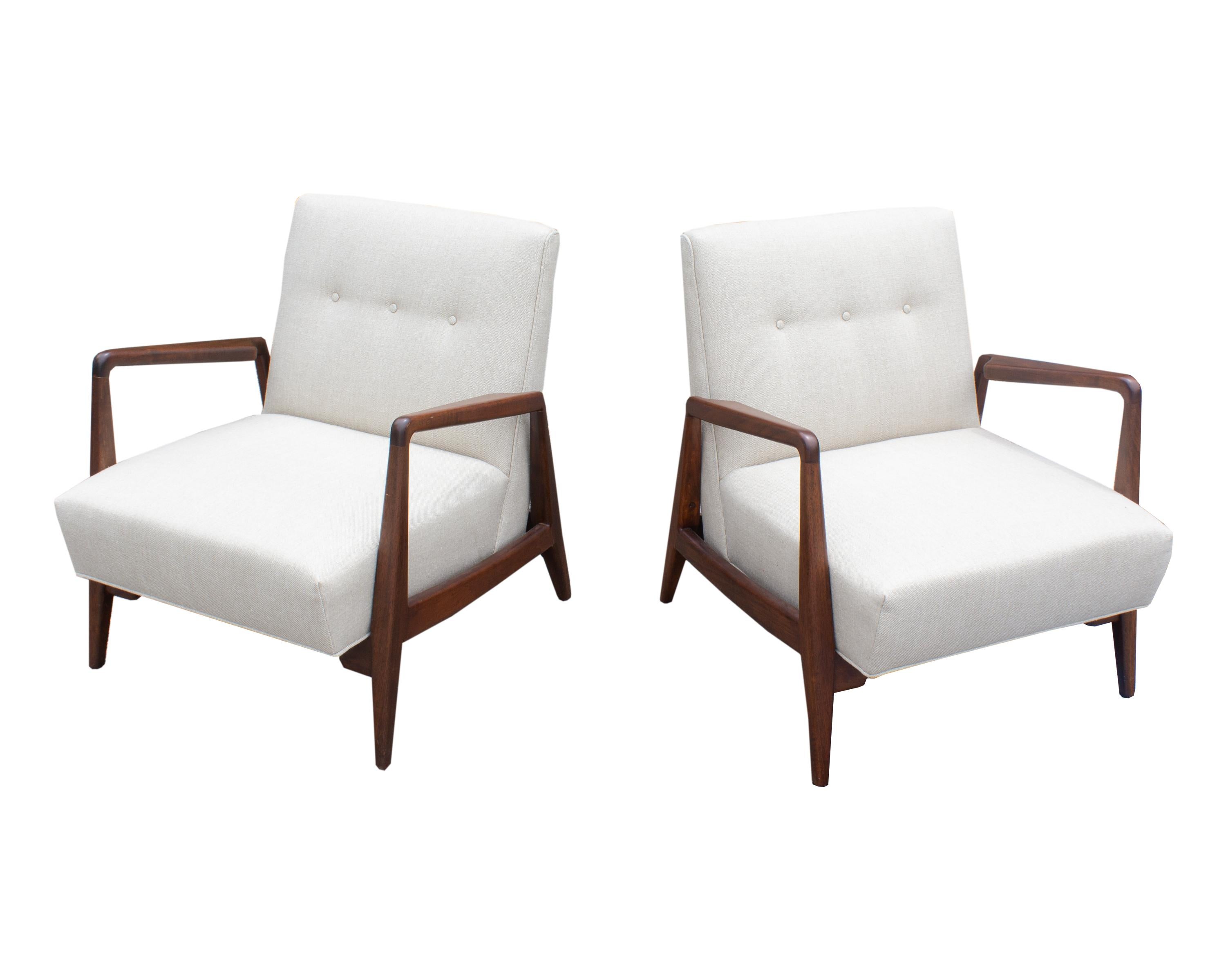 A pair of lounge chairs designed by the Danish designer Jens Risom (1916-2016). Newly upholstered, these chairs feature a walnut wood frame and a tufted back. The chairs are unmarked.

