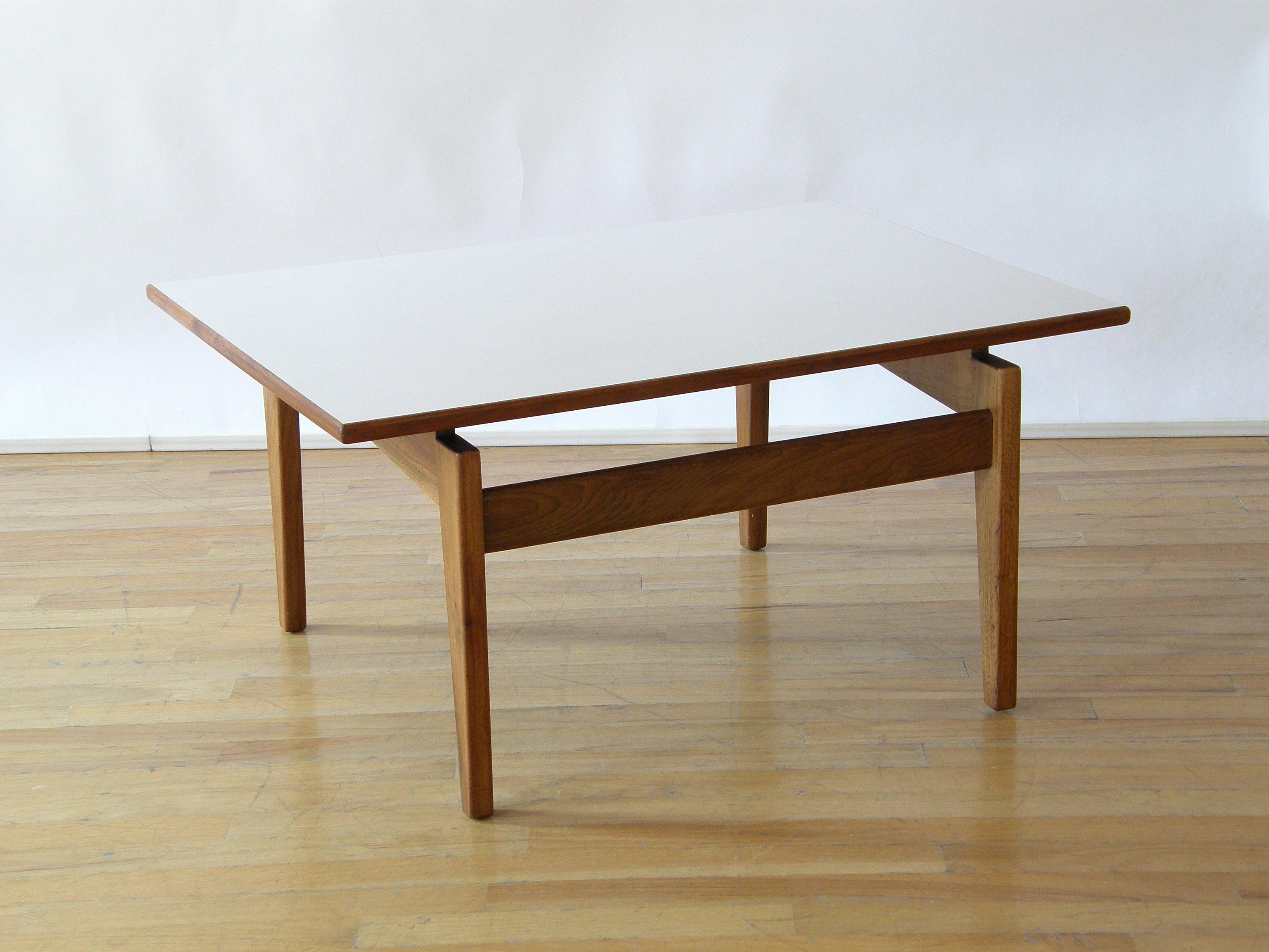 Cette table d'appoint rectangulaire de Jens Risom a une base en noyer et une surface en stratifié blanc. Les pieds sont astucieusement insérés, ce qui confère au plateau un caractère flottant et une allure globalement décontractée à la table.

   