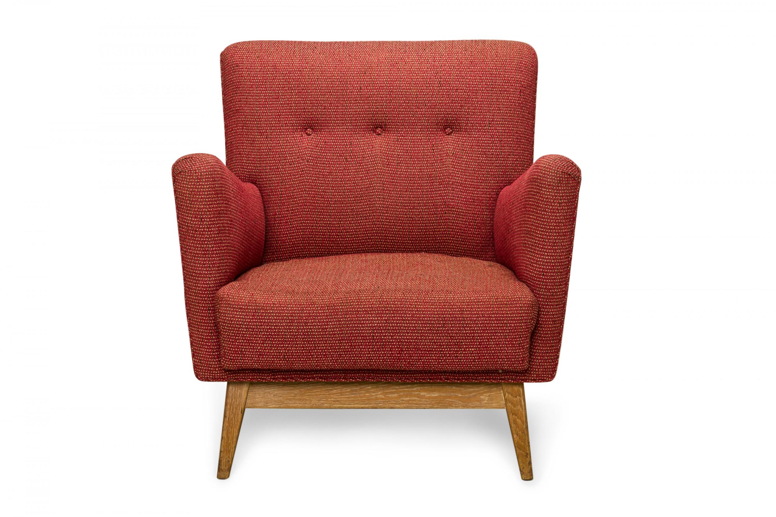 Danish mid-century lounge armchair with angled armrests and a square back, upholstered in a woven red fabric upholstery with button tufting, resting on a blonde wood base with four rounded tapered legs. (JENS RISOM)
 