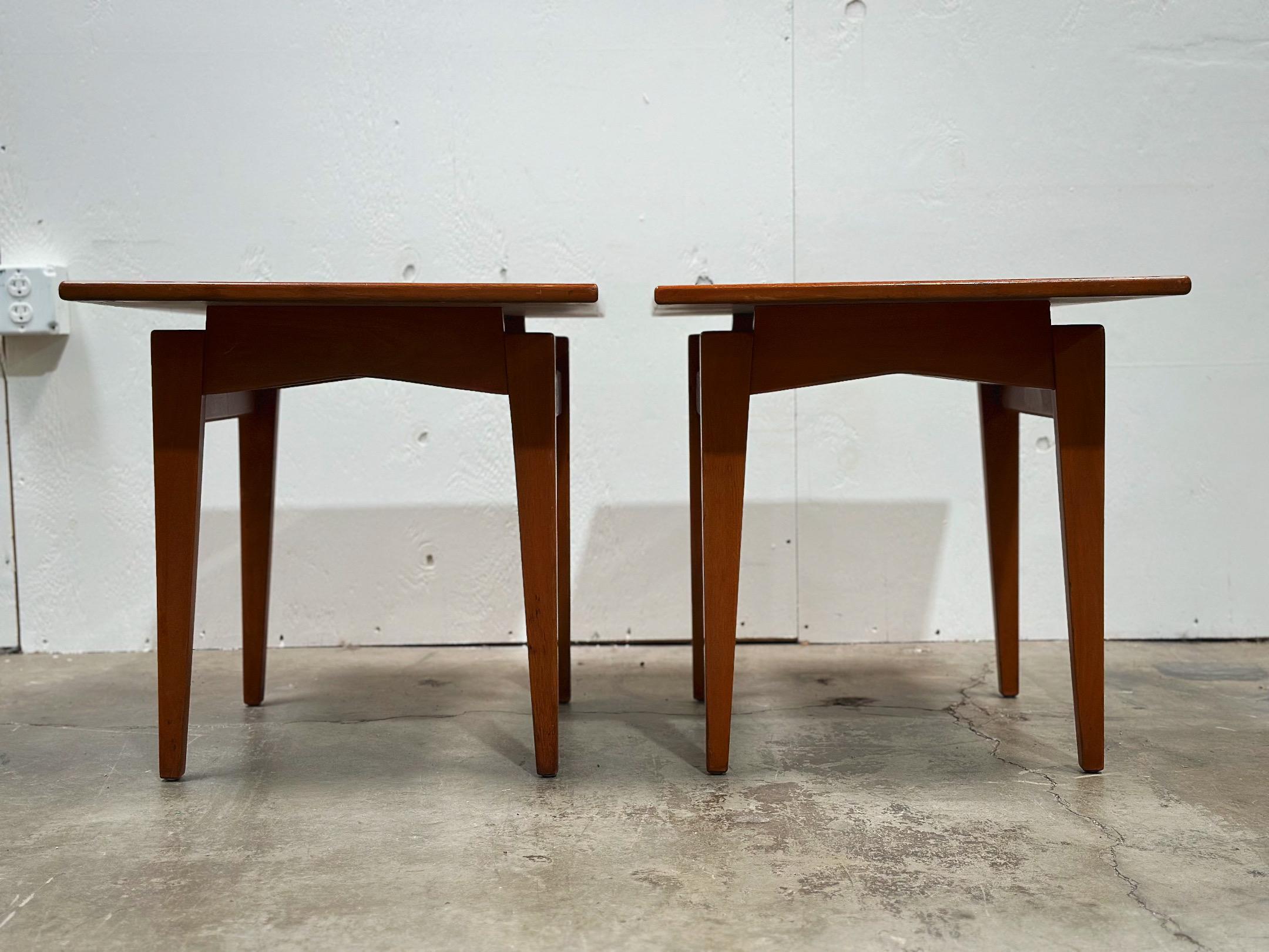Pair of mid century modern side or end tables by Jens Risom for his company, Jens Risom Design. Classic floating silouhette. Frames are a medium tone solid American walnut. Tops are solid wood with a white formica inlay. Excellent overall condition