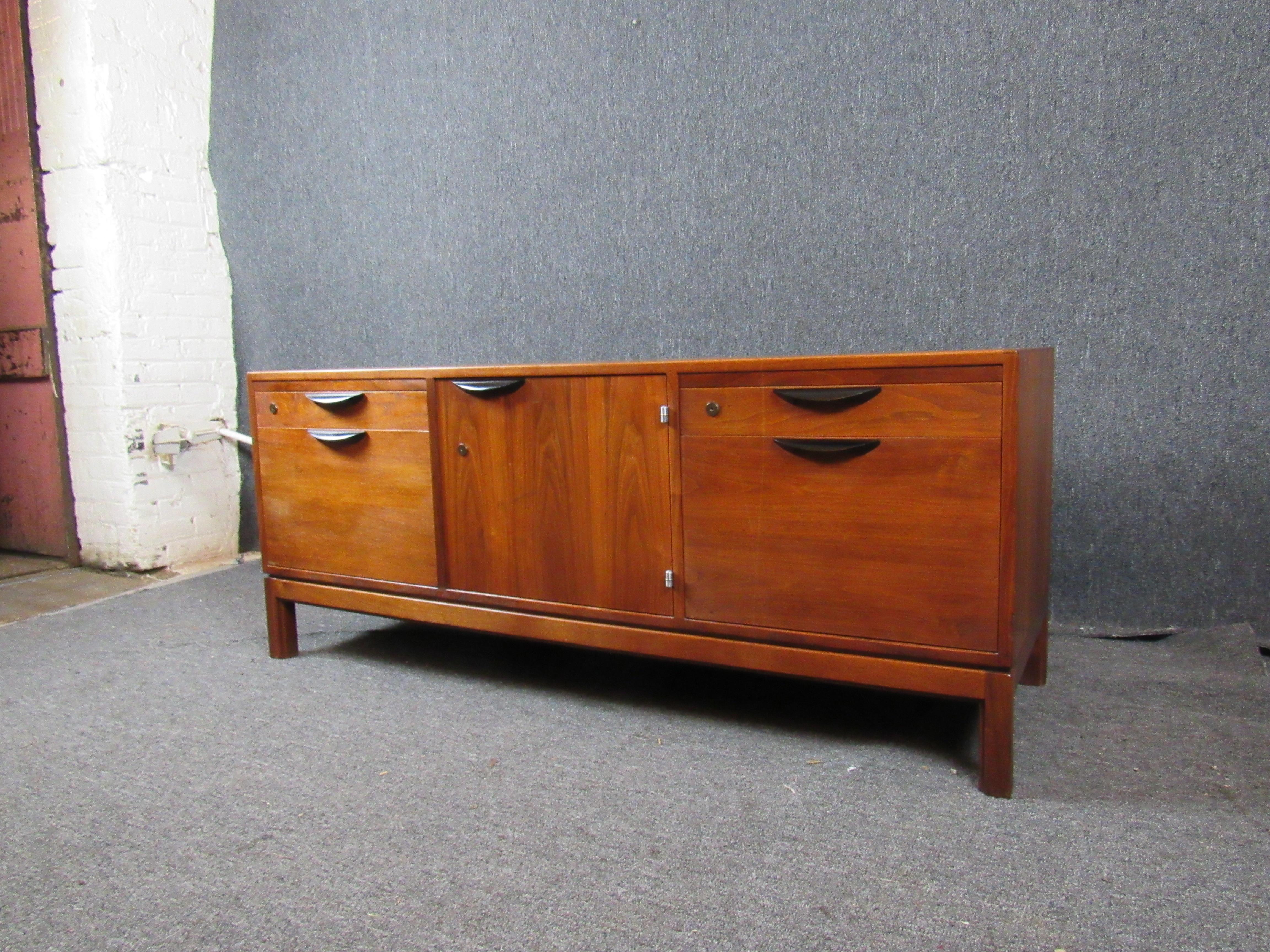 Gorgeous sideboard designed by one of the pioneers of mid-century furniture design, Jens Risom. Fine wood grain and bold lines come together in a sideboard that is equal parts beauty and utility. Four pull-out side drawers and a large center cabinet
