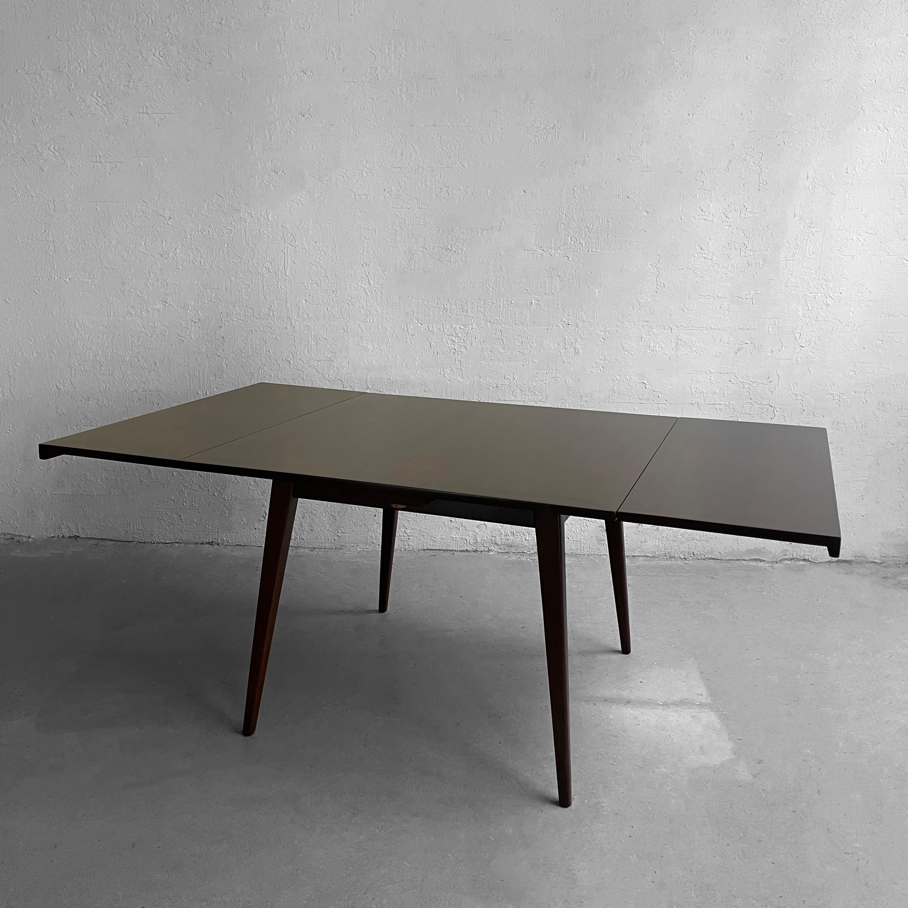 Mid-century modern, walnut, draw-leaf, extension dining table by Jens Risom features two 16 inch leaves that extend the table to 72 inches wide. The leaves tuck underneath the table and can easily be pulled out to extend.